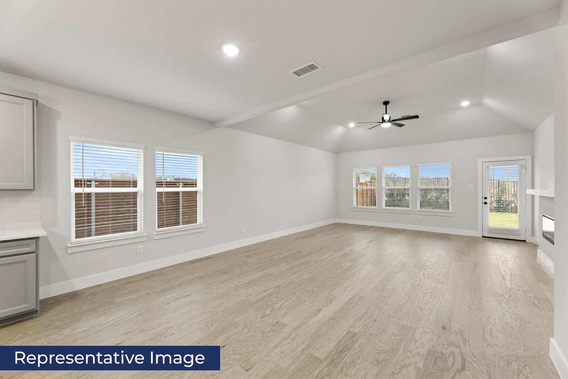 Spacious living room with wood flooring and large windows.