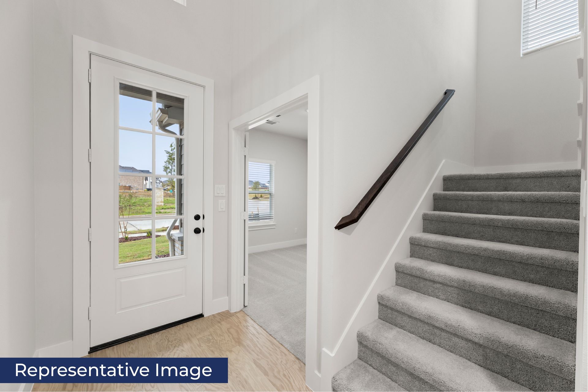 Modern entryway with carpeted stairs and glass door.