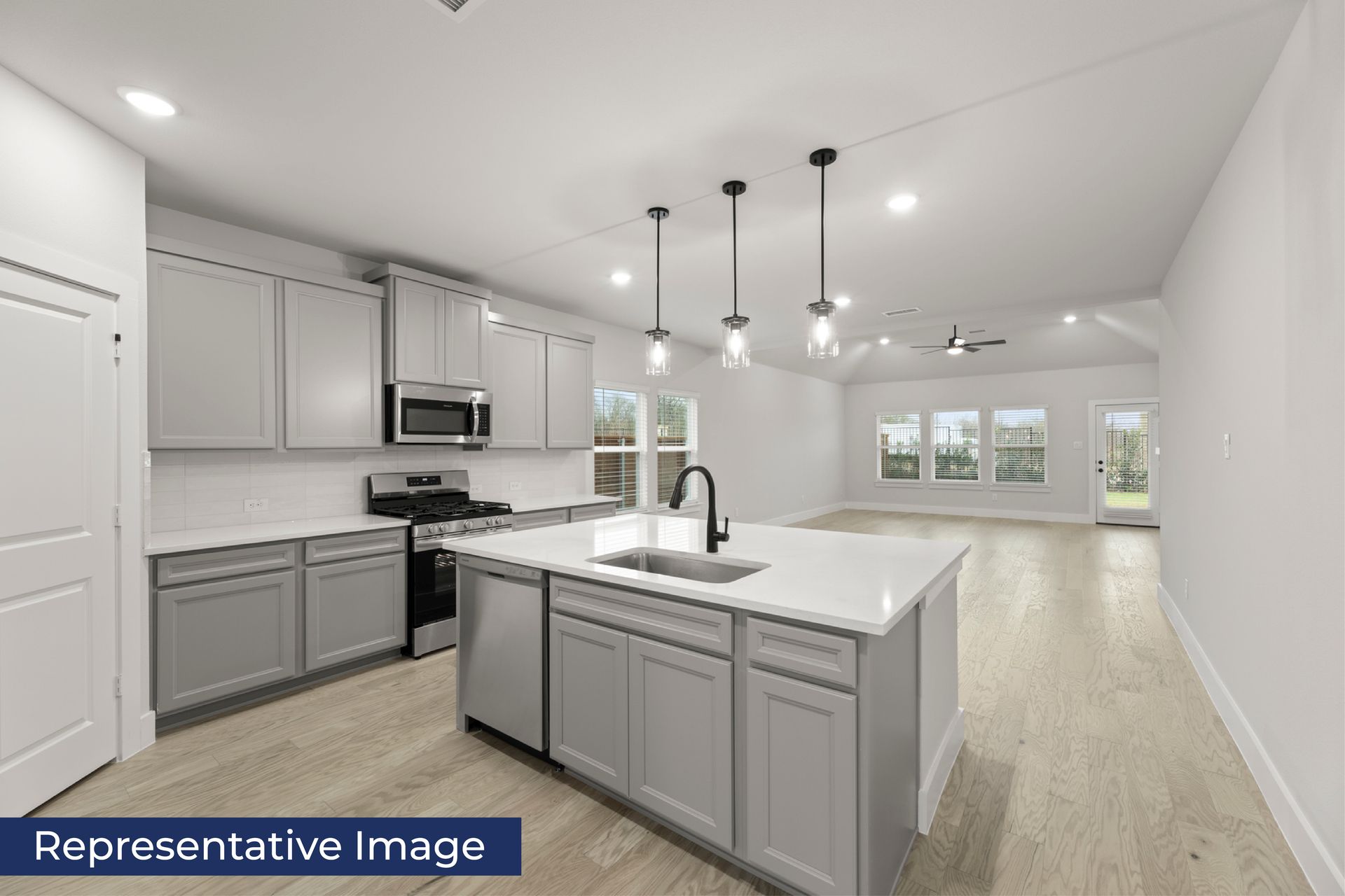 Modern kitchen with gray cabinets and open living area.