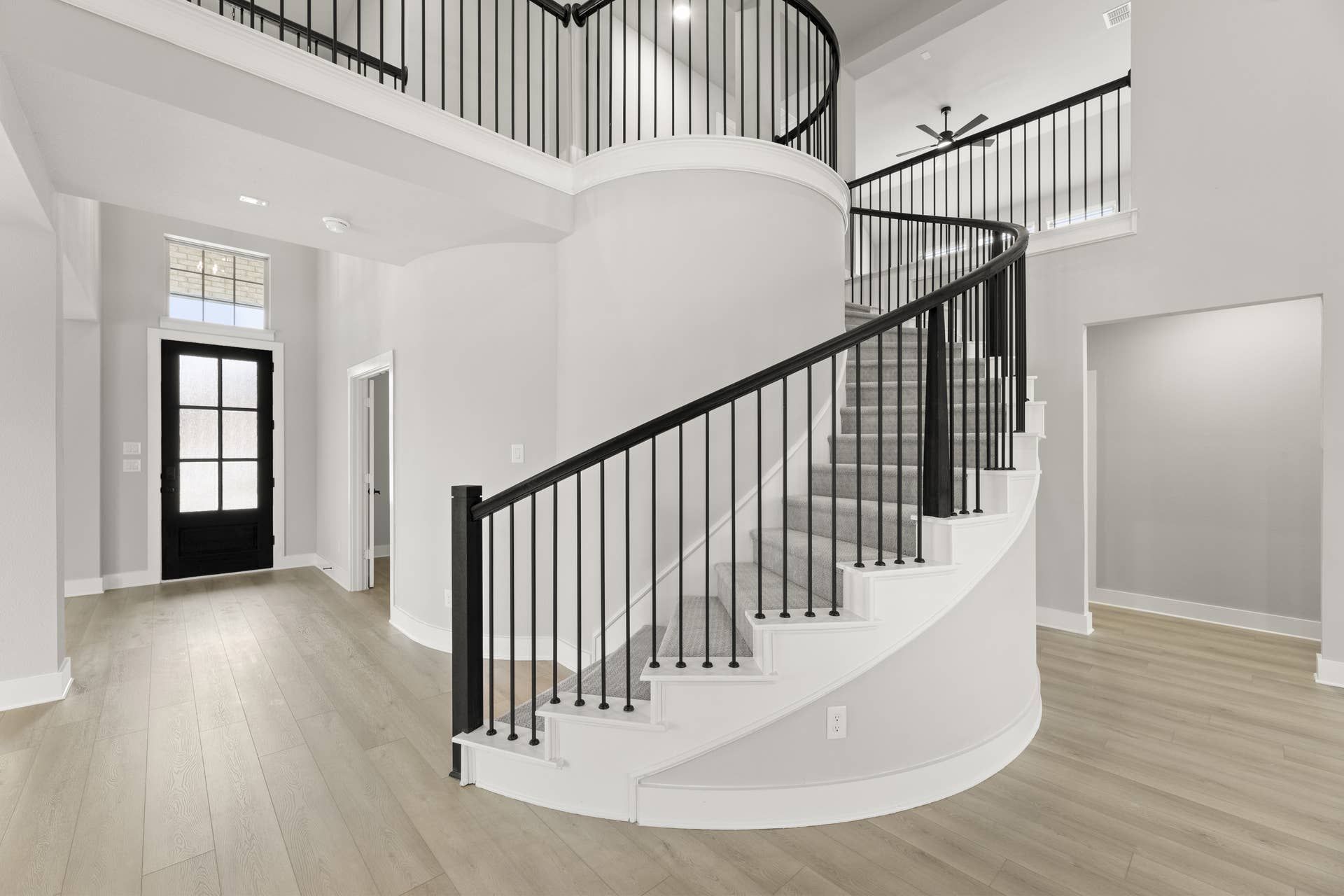 Elegant entryway with curved staircase and modern black railing.