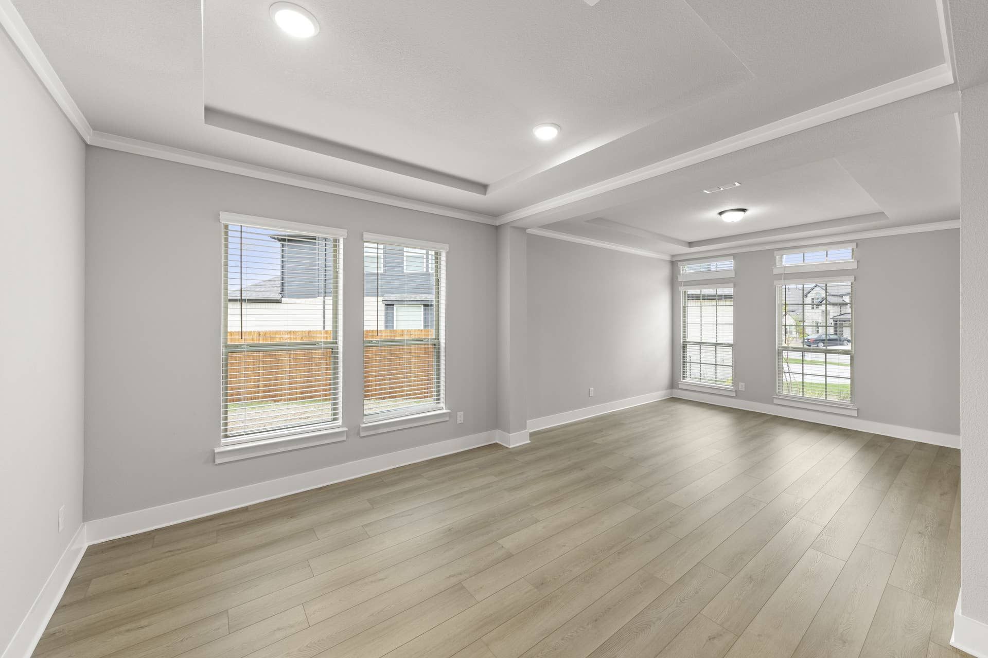 Spacious dining room with tray ceiling and large windows.