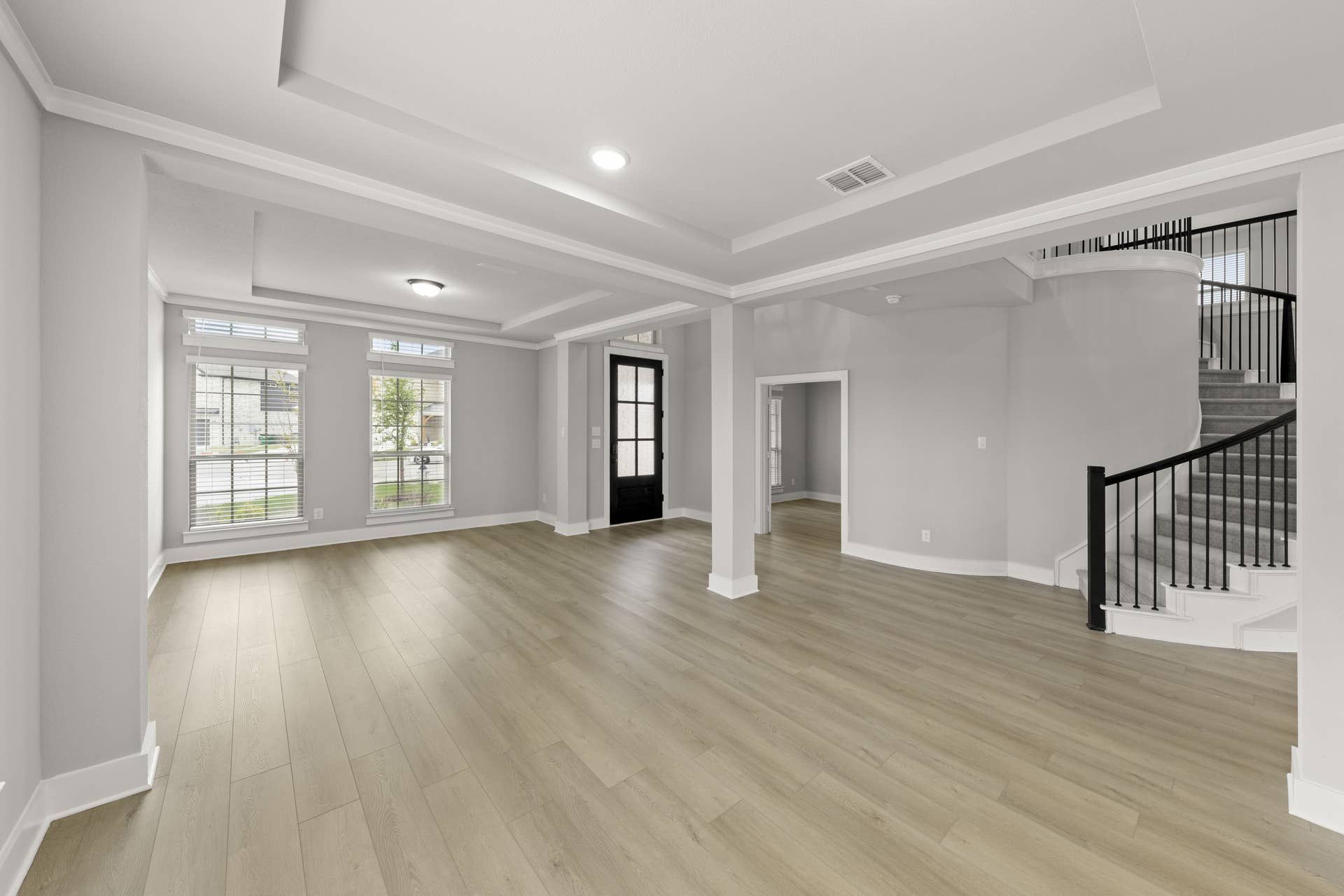 Spacious dining area with light wood flooring and elegant staircase.