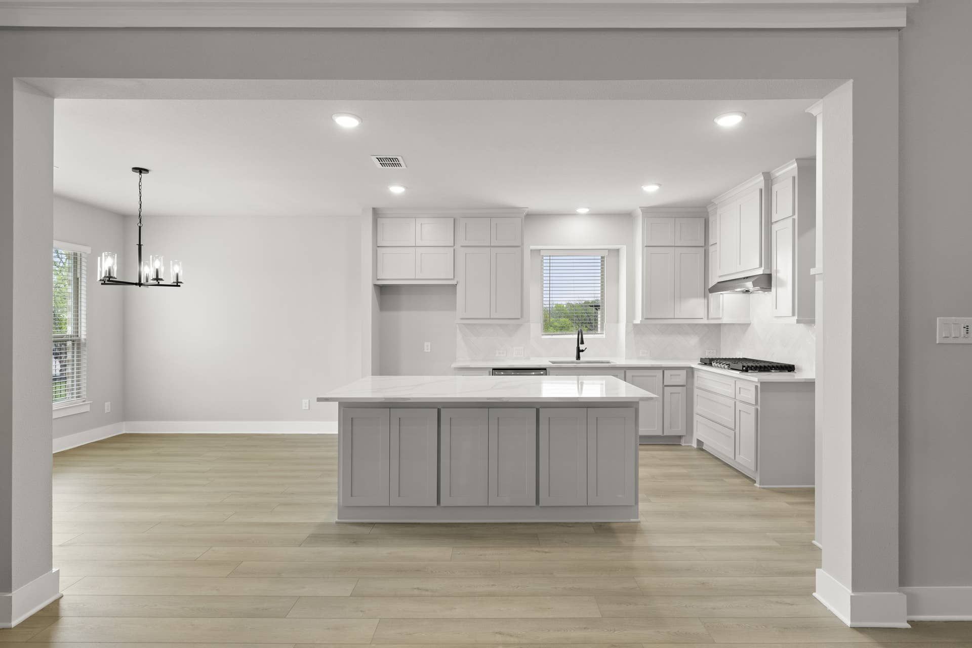 Modern kitchen with white cabinets, island, and hardwood floors.