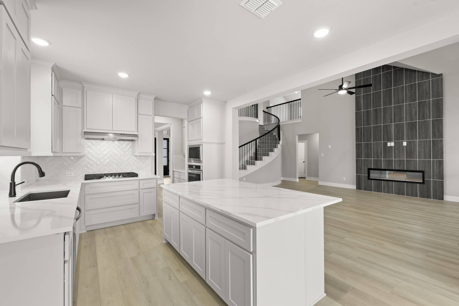 Spacious modern kitchen with white cabinetry, marble island, and herringbone backsplash.
