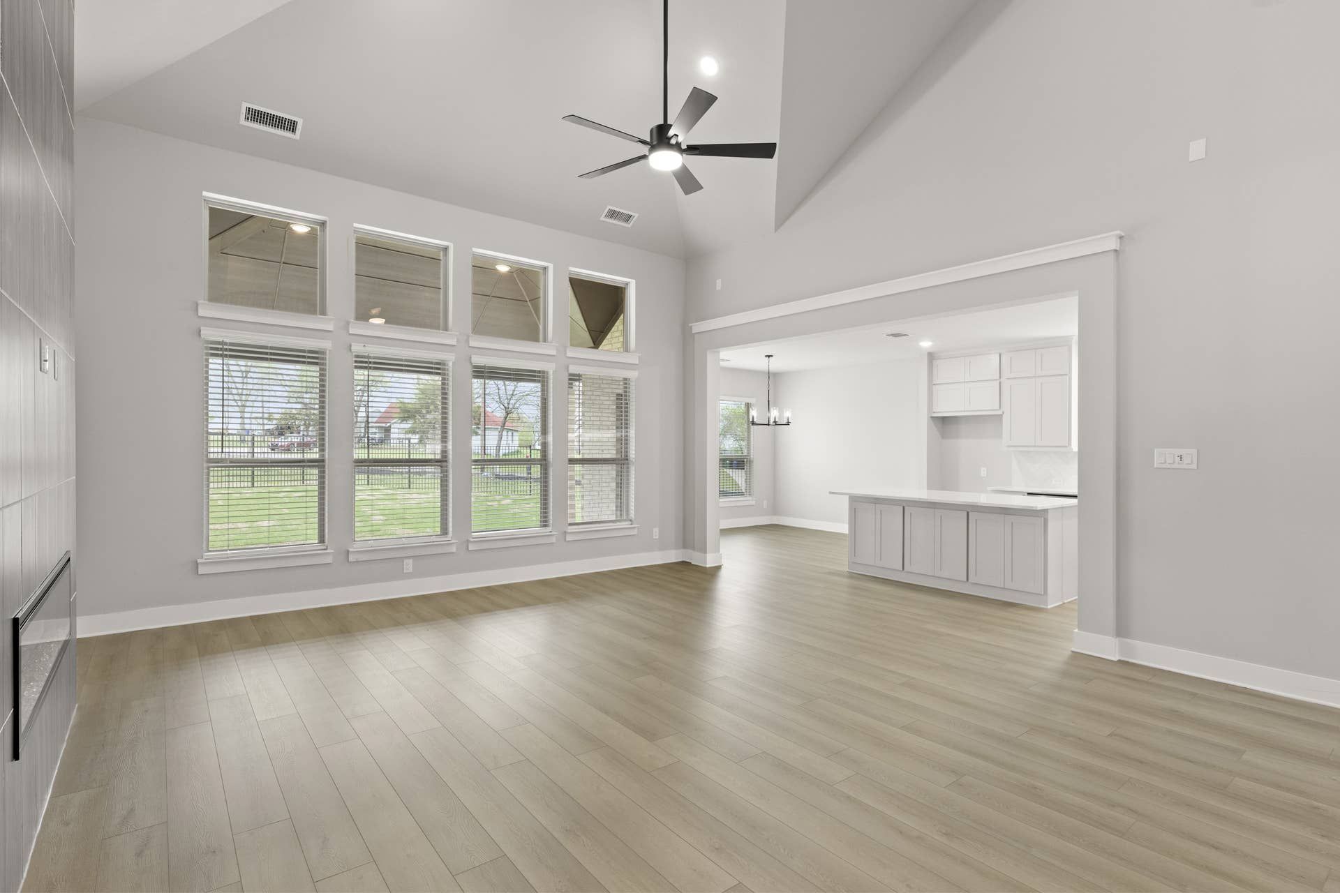 Spacious living room with high ceilings, large windows, and open layout to kitchen.