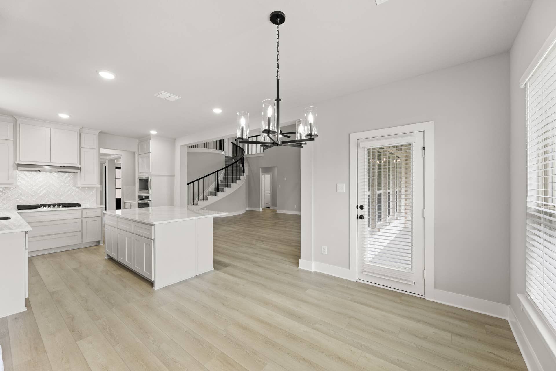 Spacious kitchen nook with island, chandelier, and spiral staircase.