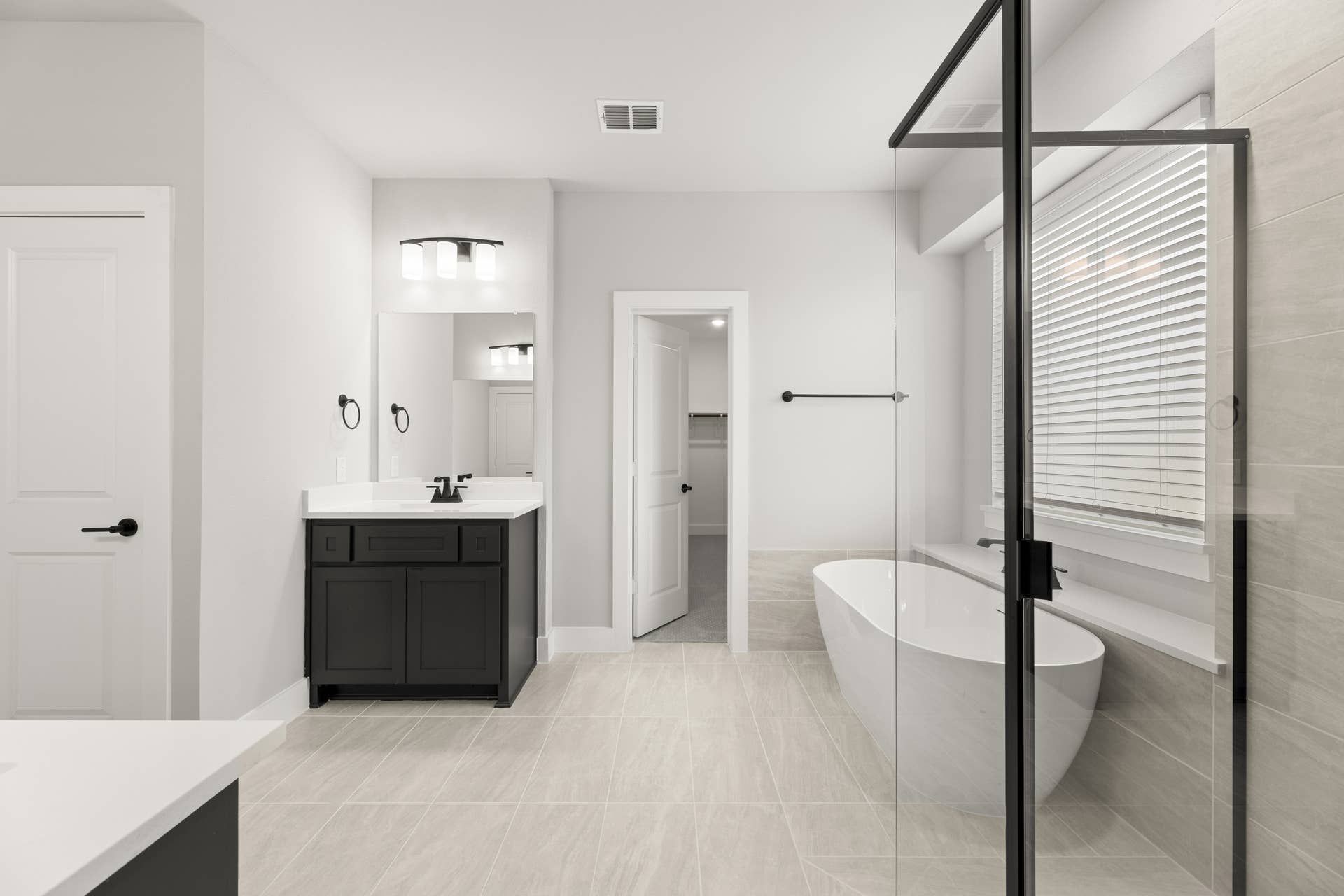 Modern bathroom with freestanding tub, glass shower, and dark vanity.