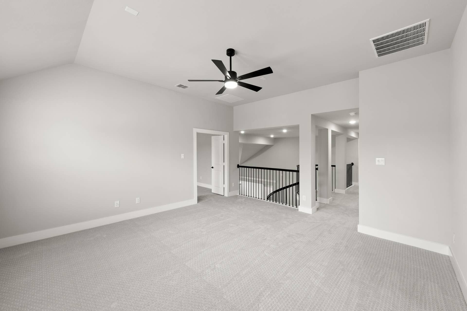 Spacious game room with ceiling fan and carpeted flooring.
