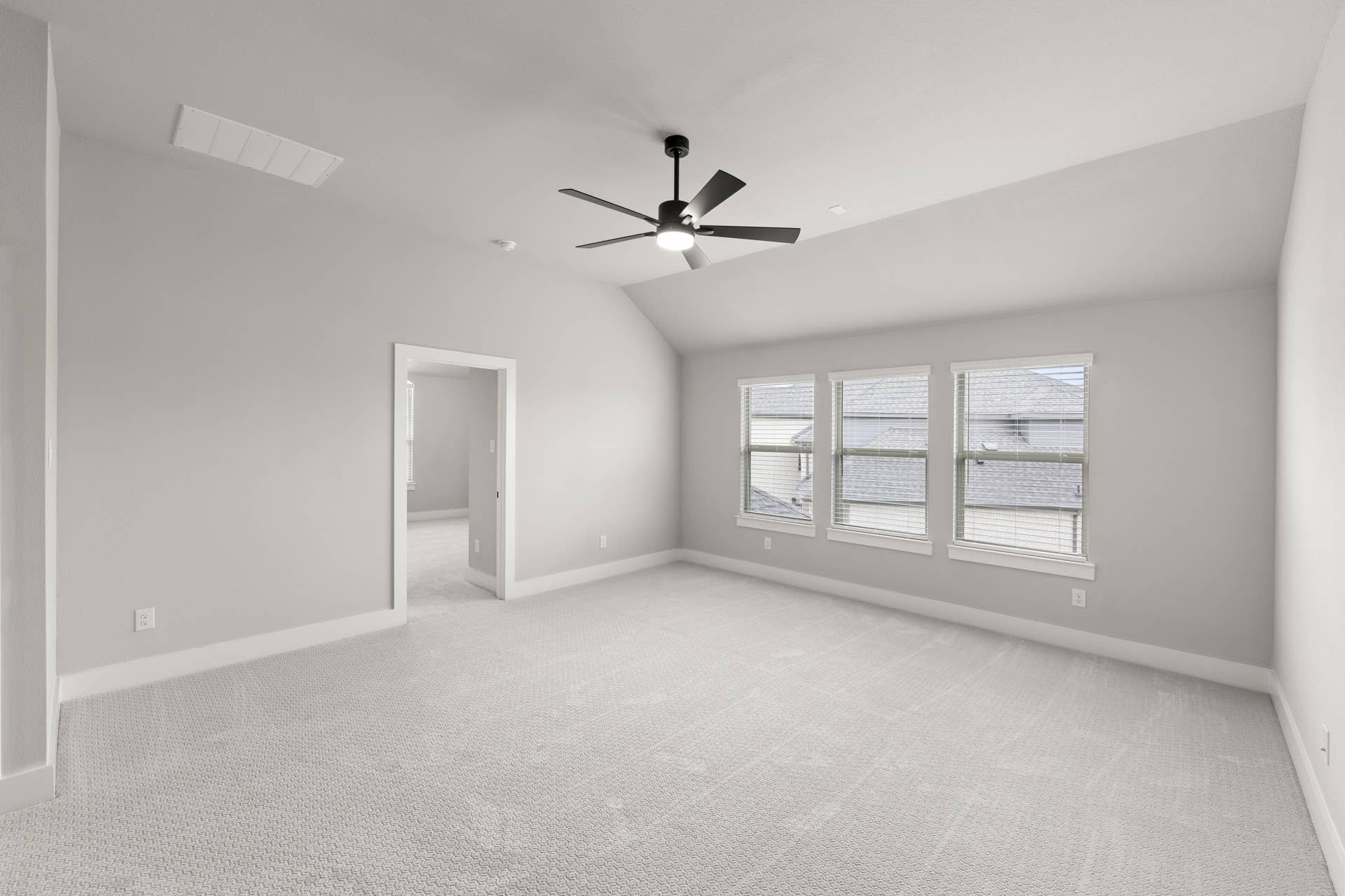 Spacious bedroom with vaulted ceiling, ceiling fan, and large windows.