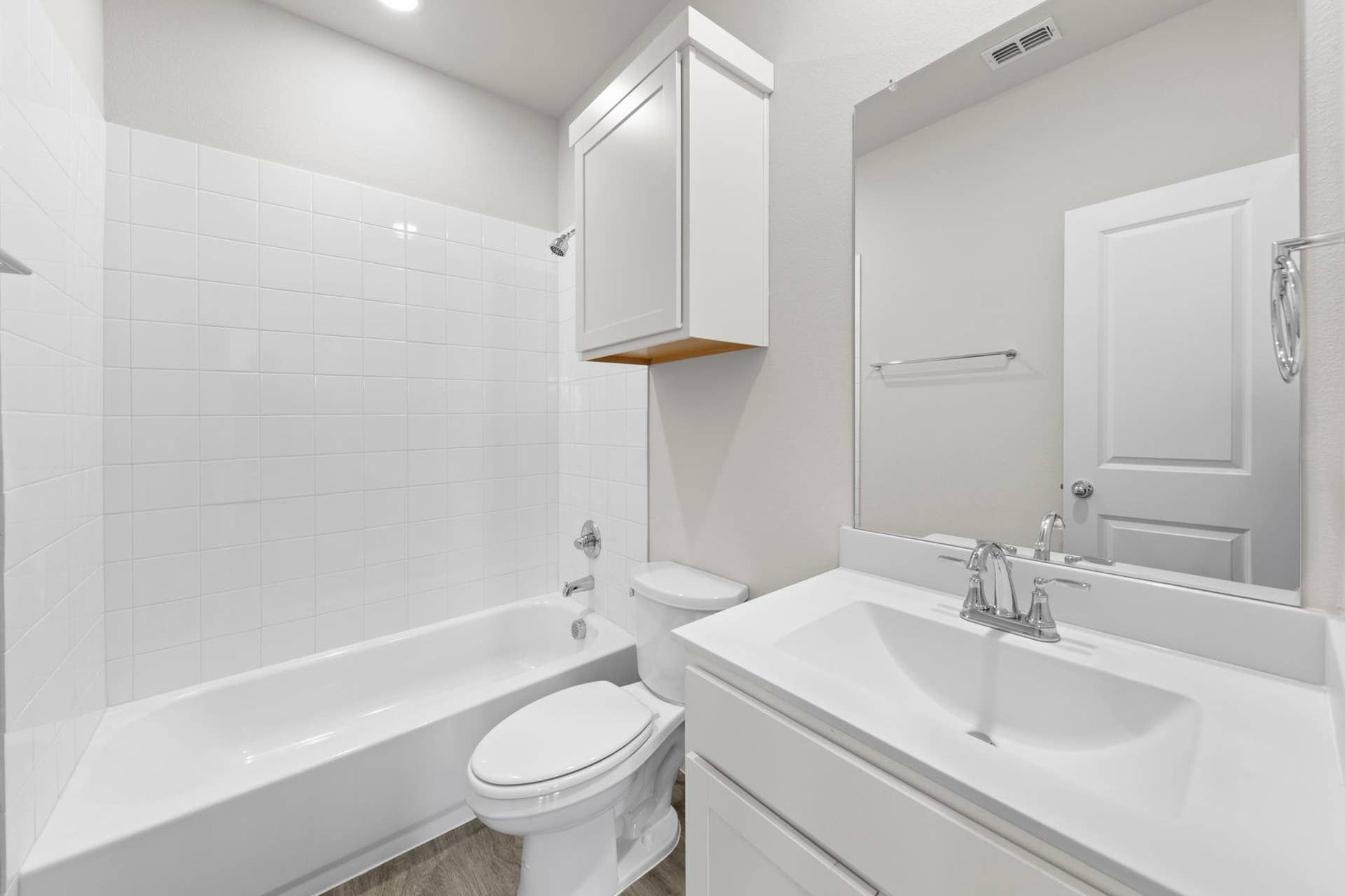 Modern bathroom with white tile, bathtub, and vanity sink.