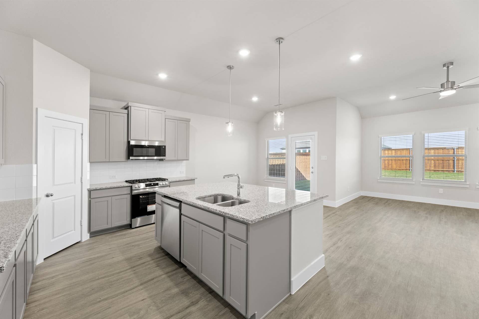 Modern kitchen with gray cabinets, granite countertops, and open layout.