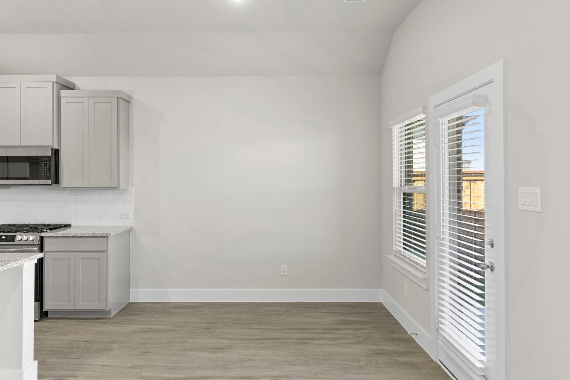 Contemporary dining area with hardwood flooring and large windows for natural light.