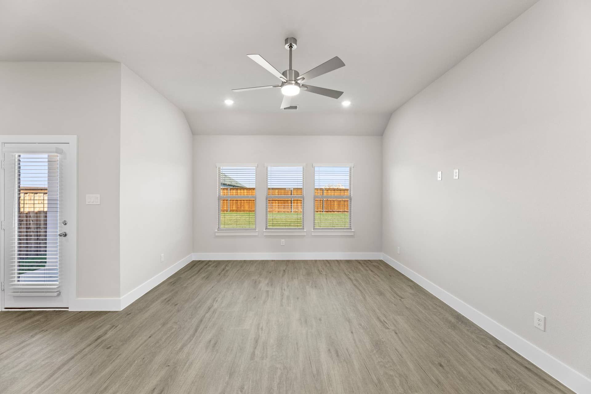 Spacious living room with ceiling fan and large windows overlooking backyard.
