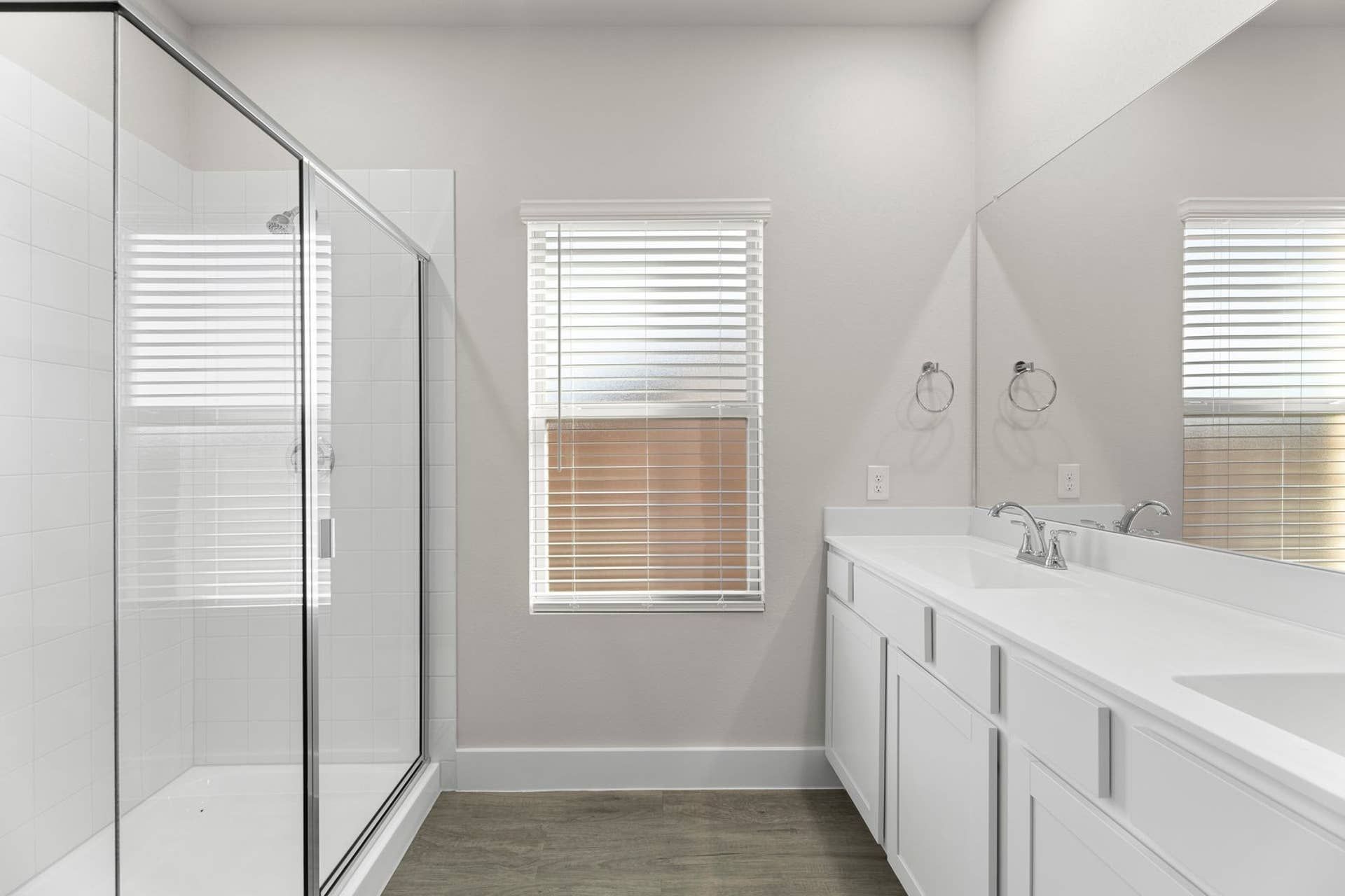 Modern bathroom with glass shower, dual sinks, and natural light.