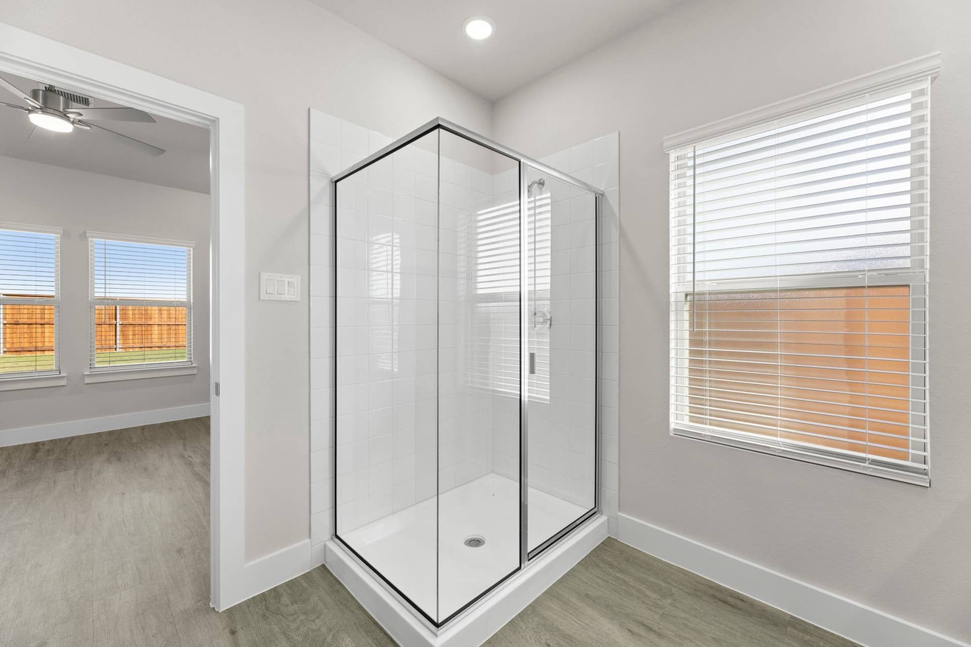 Modern bathroom with glass shower and natural light from windows.