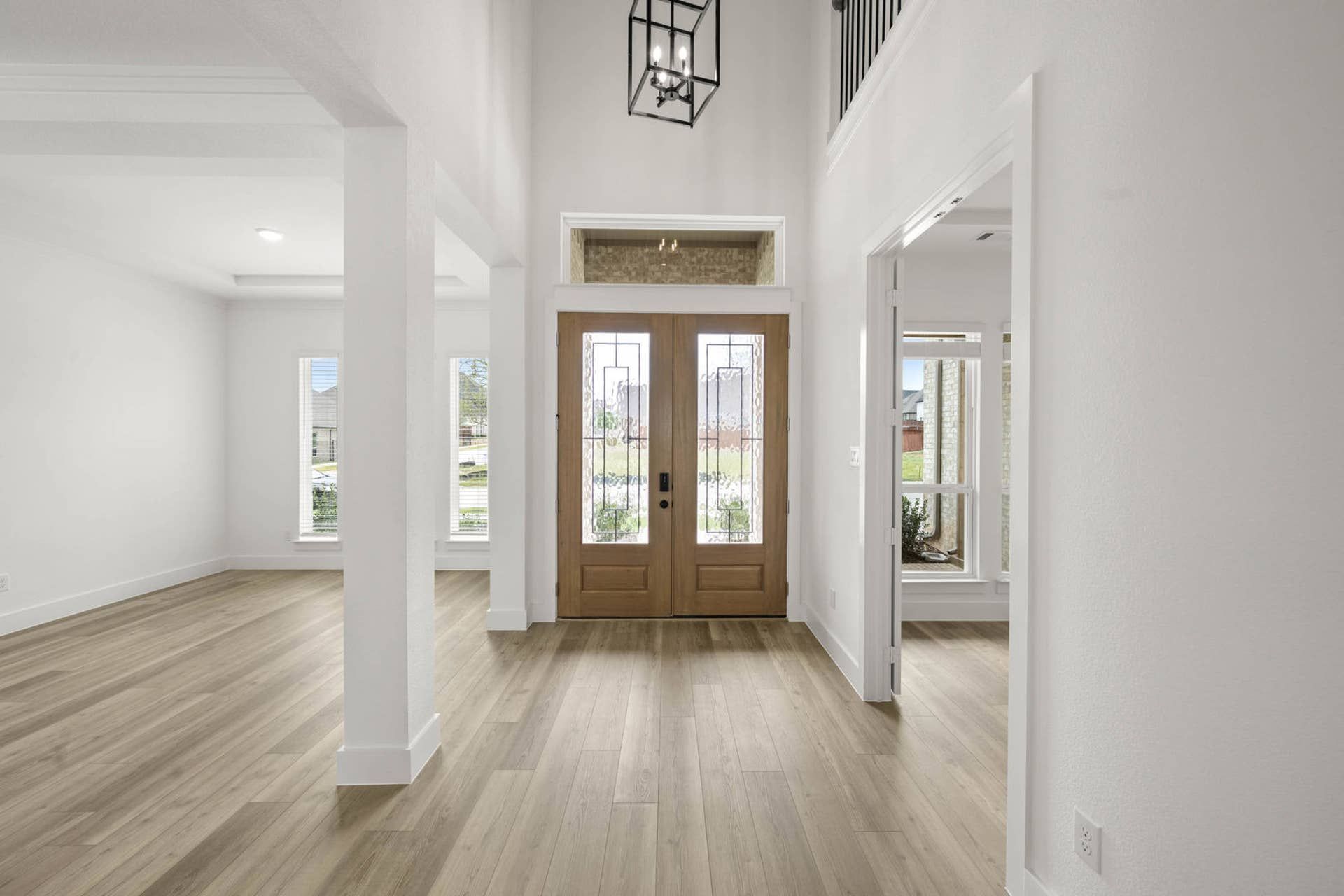 Grand two-story entry foyer with double front doors, transom window, and wood-look flooring