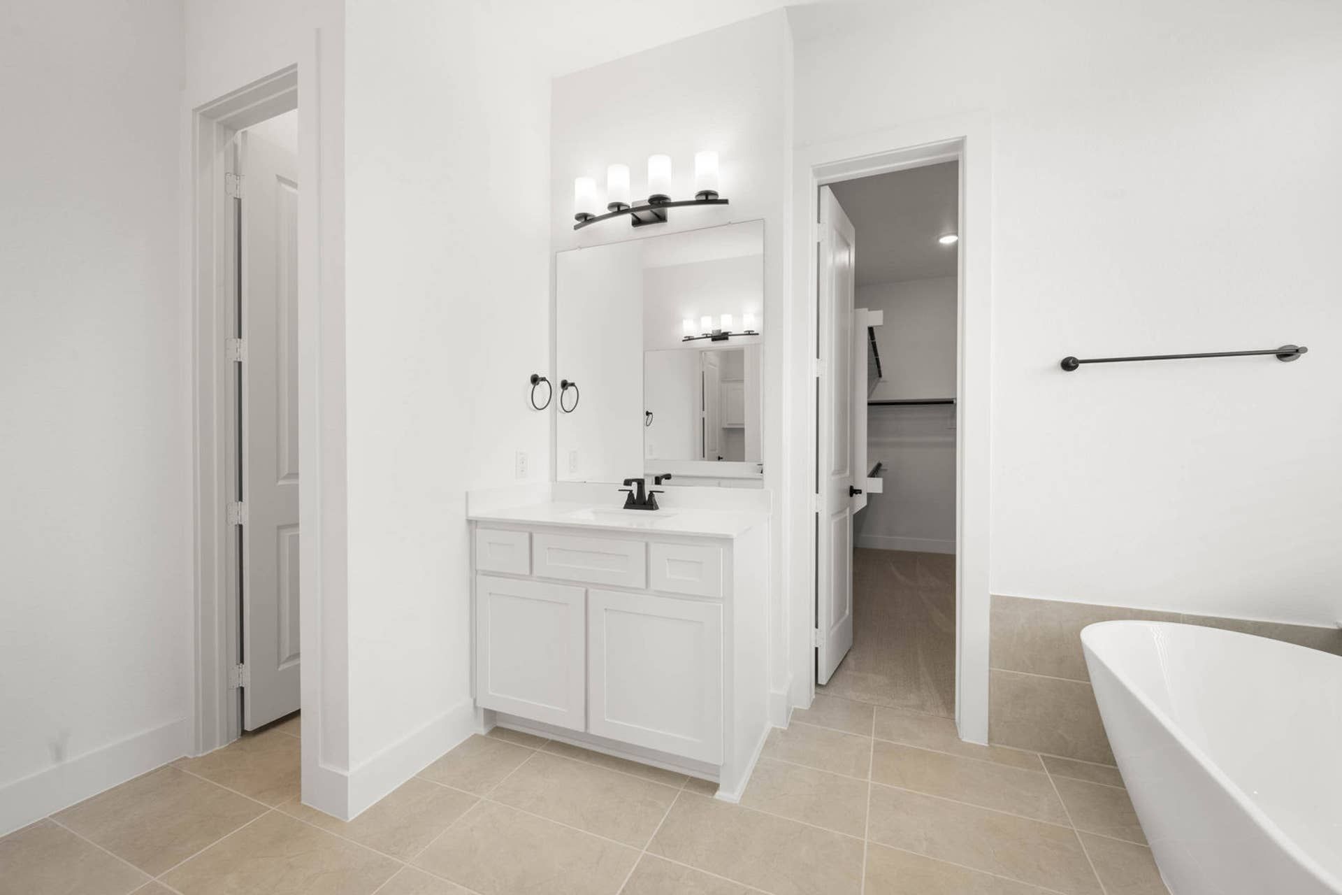 Primary suite bathroom with single vanity, walk-in closet access, and freestanding soaking tub.
