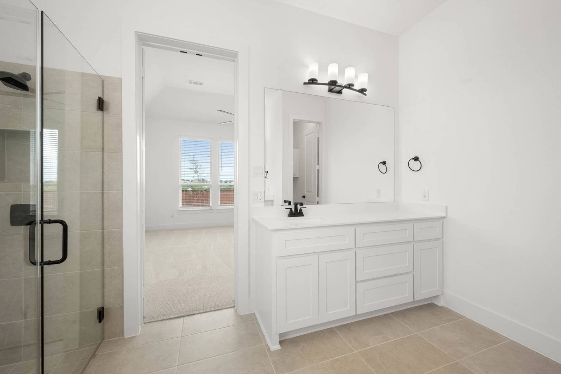 Primary suite bathroom with single vanity, large mirror, and glass-enclosed tiled shower