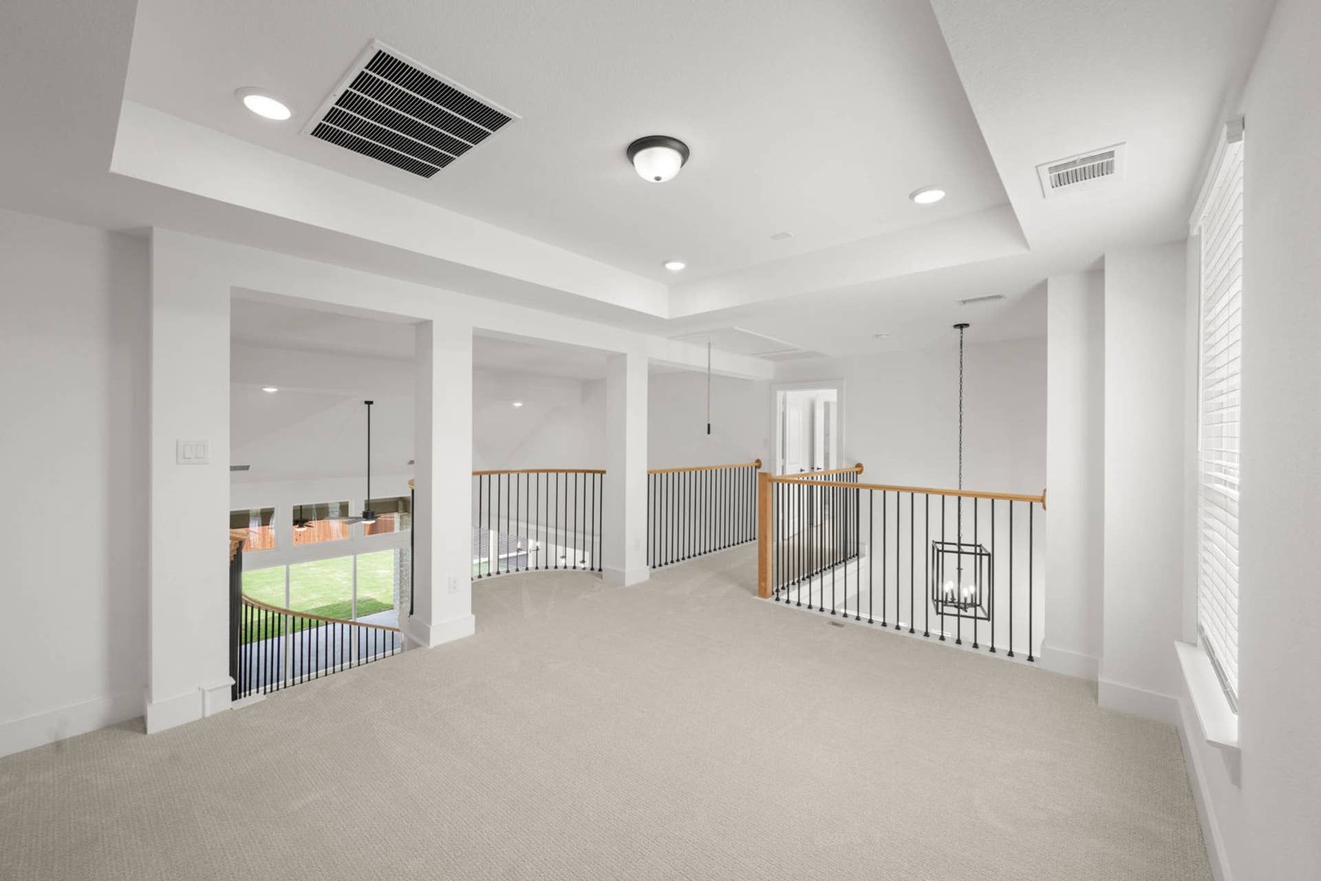 Open loft interior with tray ceiling, carpet, and iron railing overlooking below