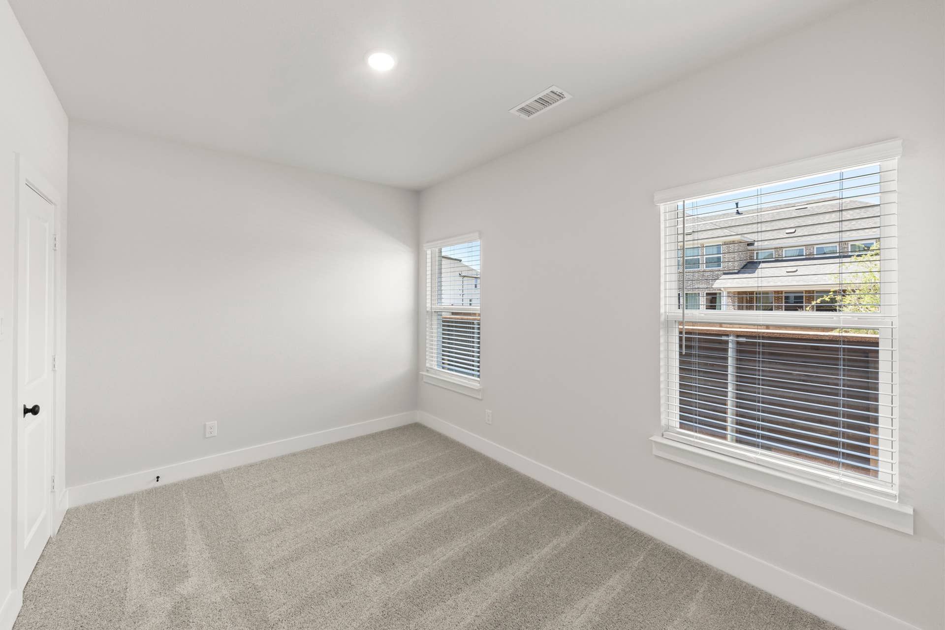 Bright secondary bedroom with carpet, two windows, white walls, and recessed lighting