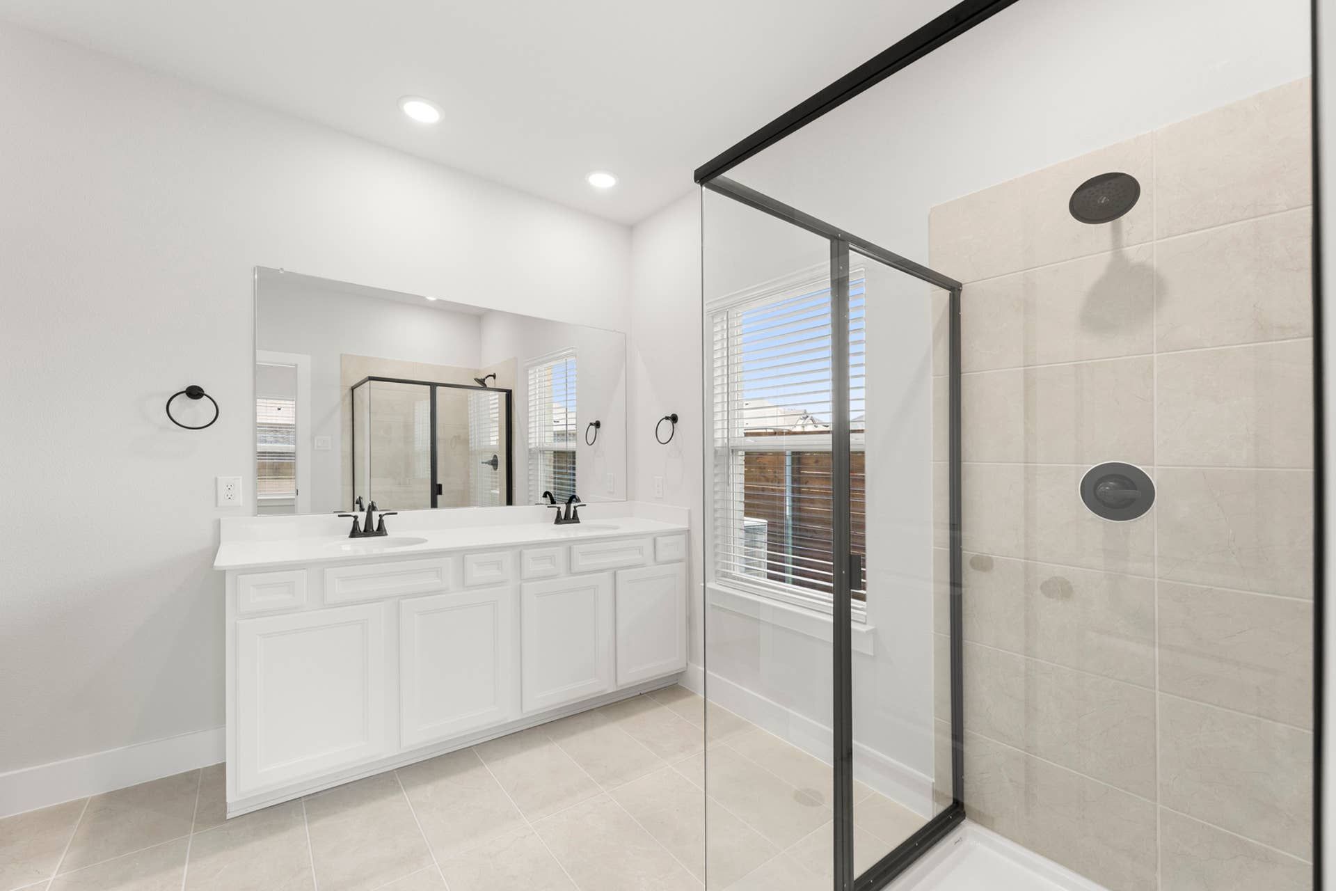Primary bathroom with dual-sink vanity and frameless glass walk-in shower