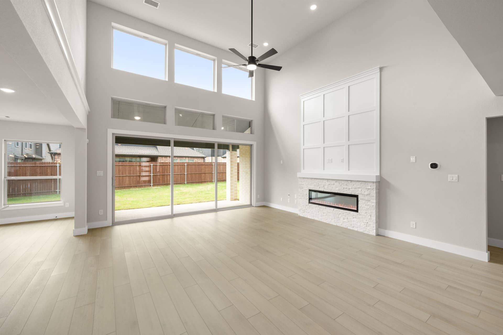 Bright living room with vaulted ceilings, large windows, sliding doors, and modern fireplace feature wall