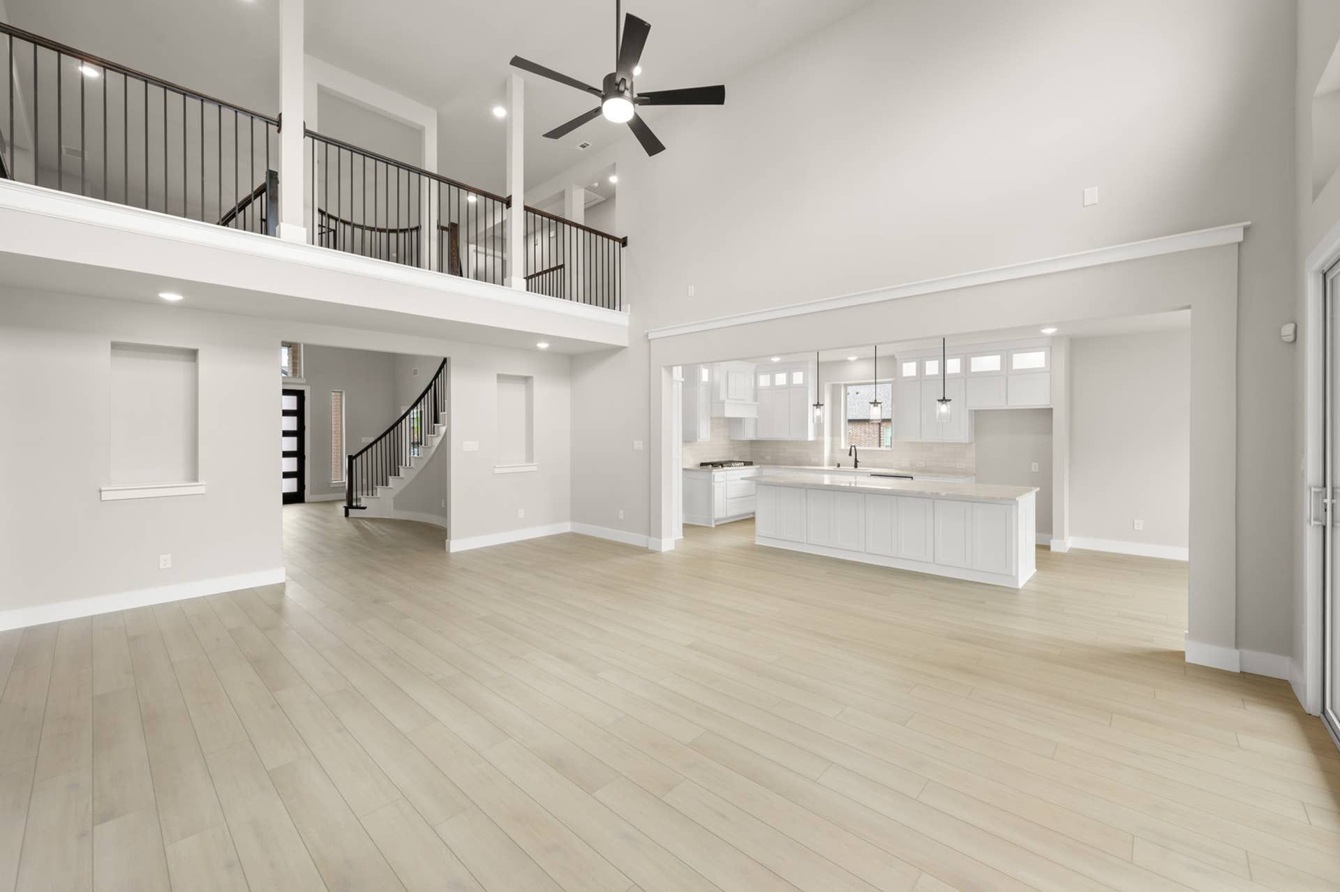 Open-concept living room with soaring ceilings, loft overlook, ceiling fan, and large kitchen island
