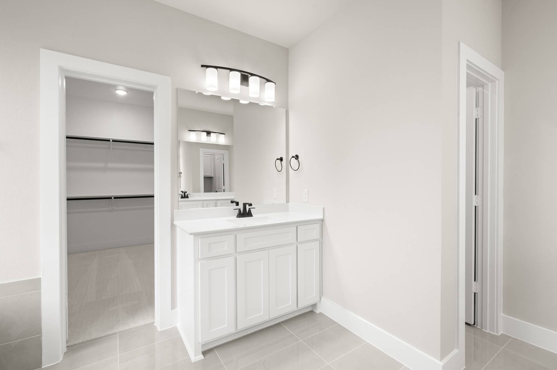 Primary suite bathroom vanity with framed mirror and adjacent walk-in closet