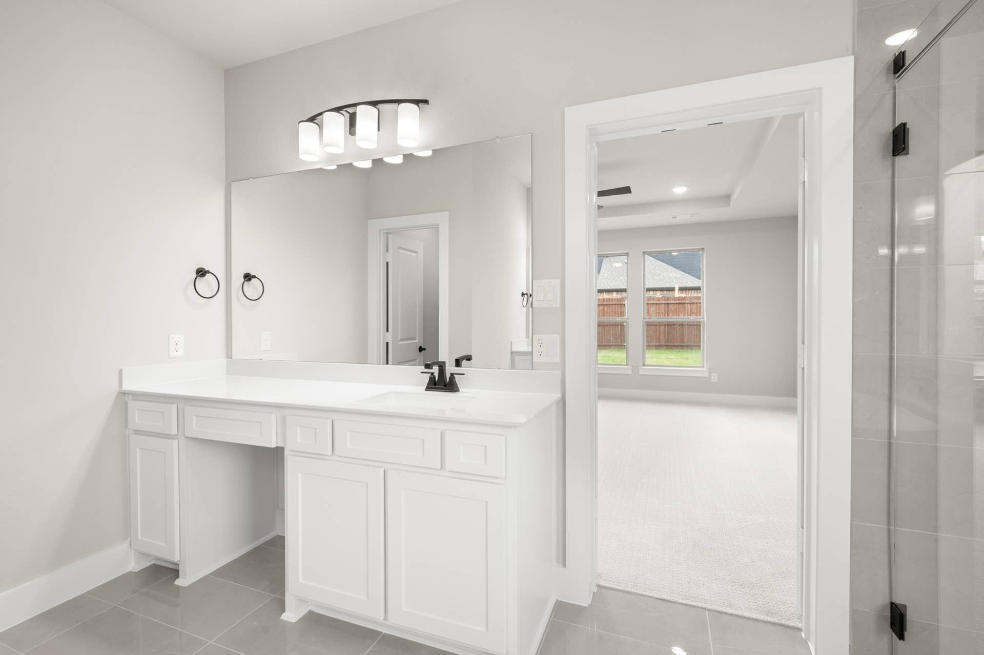Primary suite bathroom with single vanity, large mirror, and glass shower