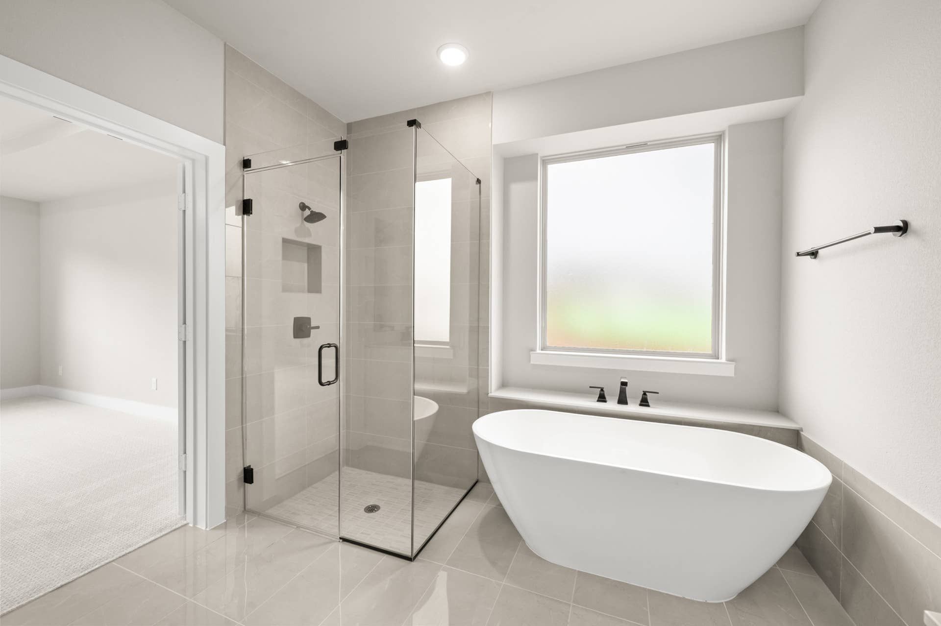 Primary suite bathroom with glass walk-in shower, freestanding soaking tub, and frosted window