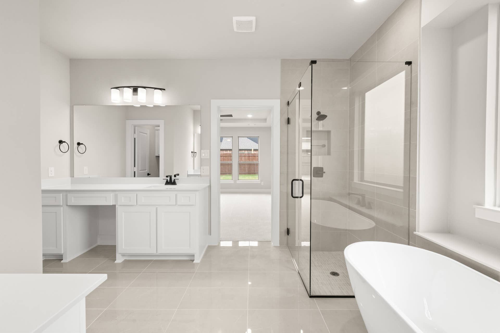 Primary suite bathroom with dual vanity, glass shower, and freestanding soaking tub