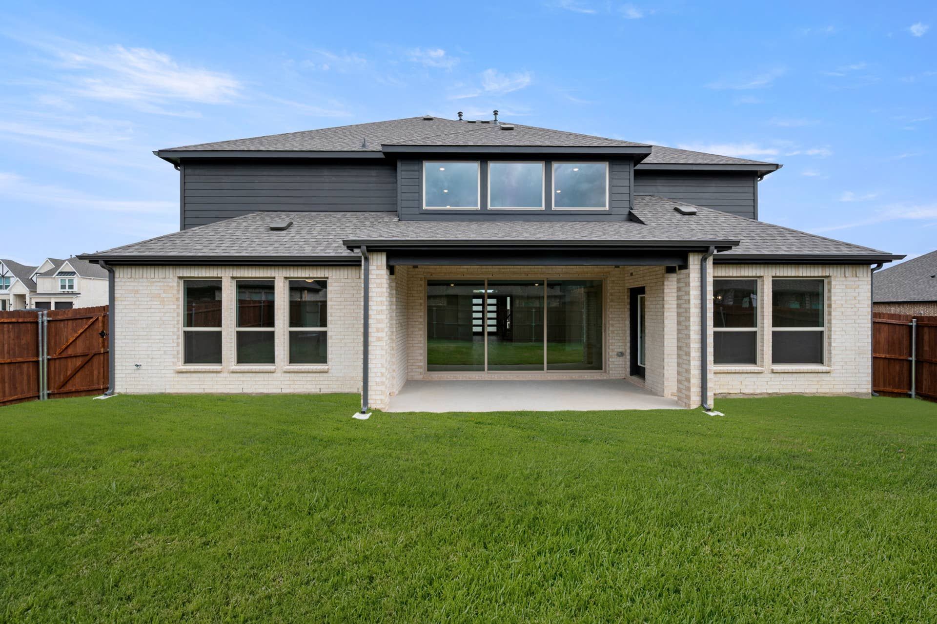 Rear elevation with covered patio, sliding glass doors, fenced yard, and two-story exterior.