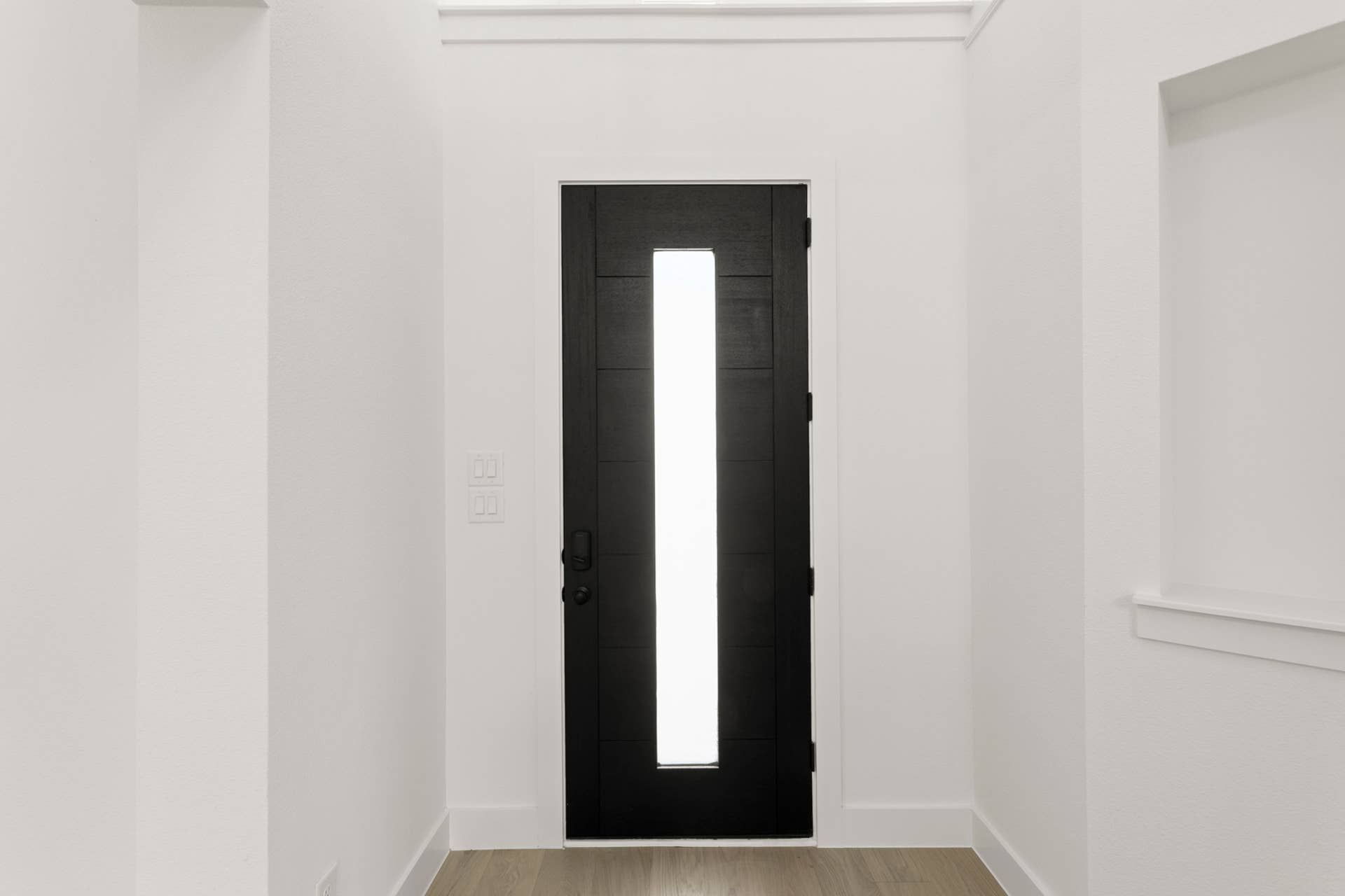 Modern entryway with a sleek black door featuring a vertical glass panel.