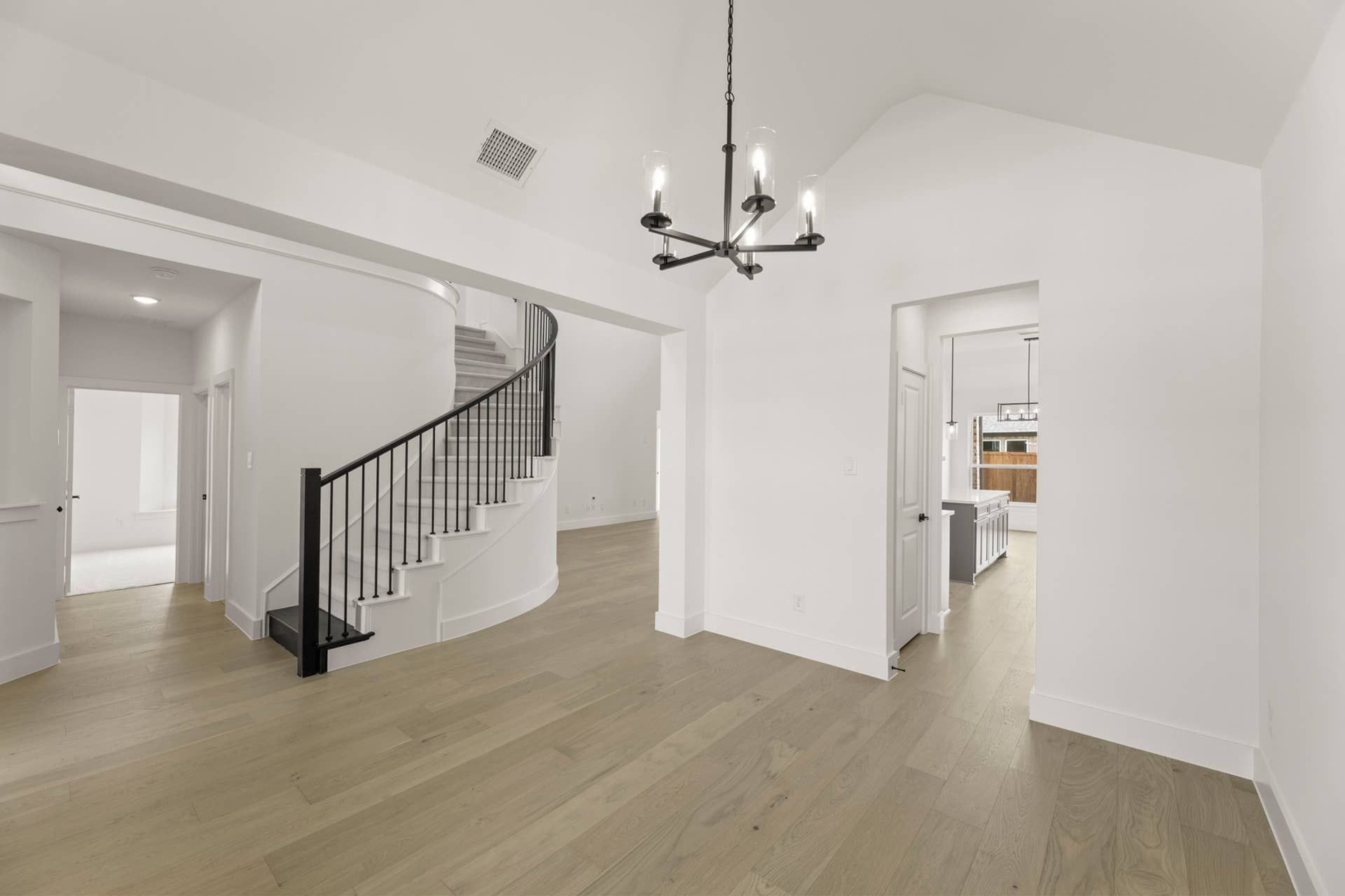 Spacious dining area with elegant chandelier and curved staircase.