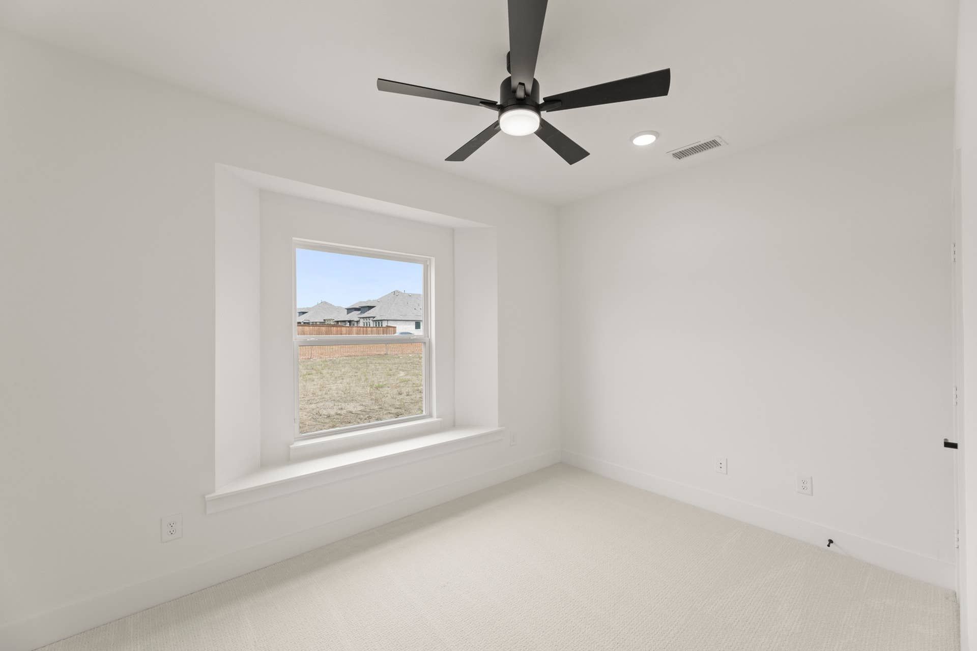 Bright study room with large window and modern ceiling fan.