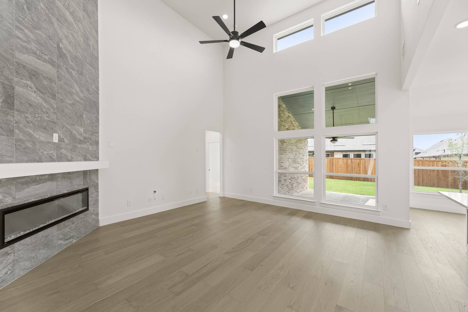 Spacious living room with high ceilings, large windows, and modern fireplace.