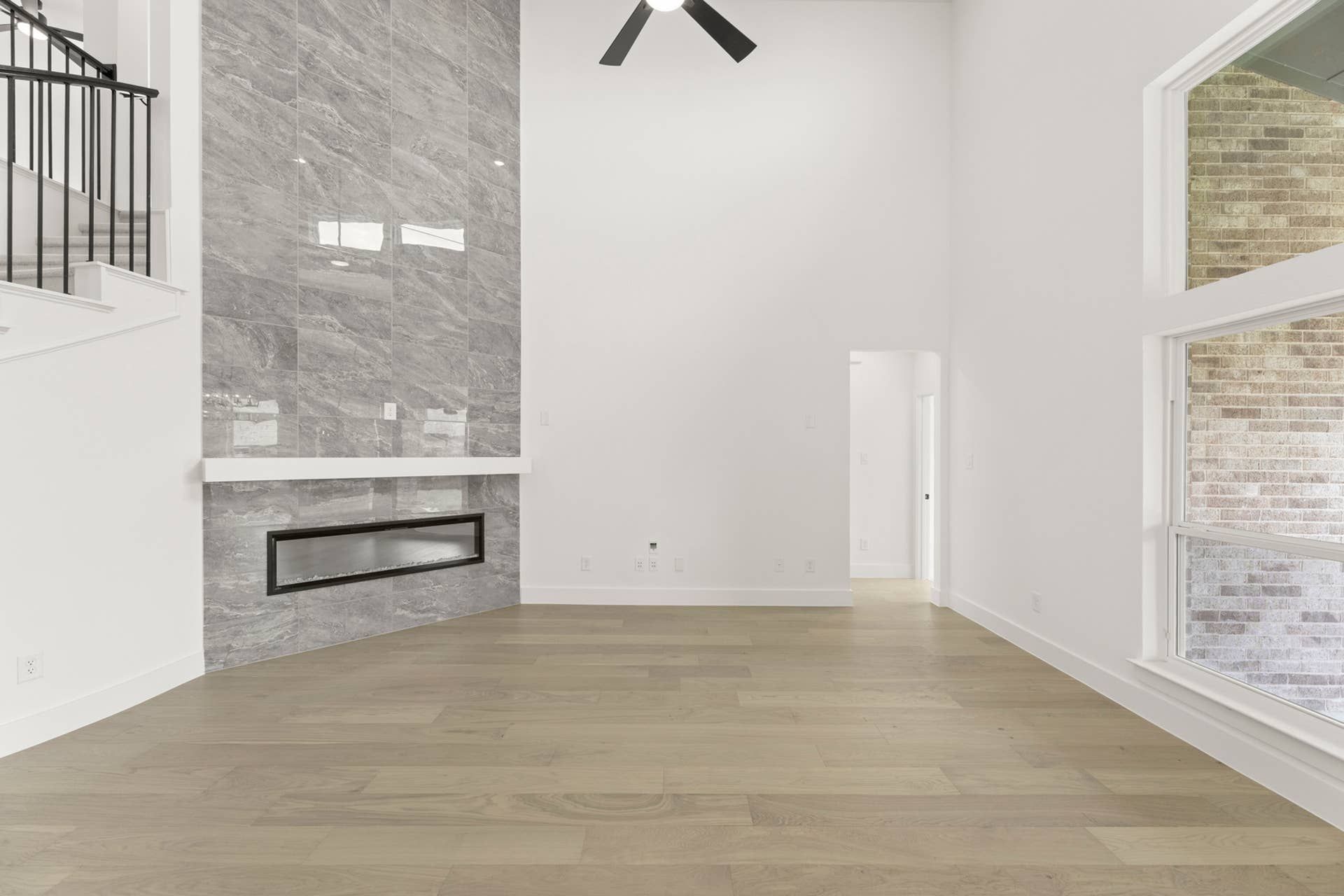 Spacious living room with high ceiling, modern fireplace, and large windows.