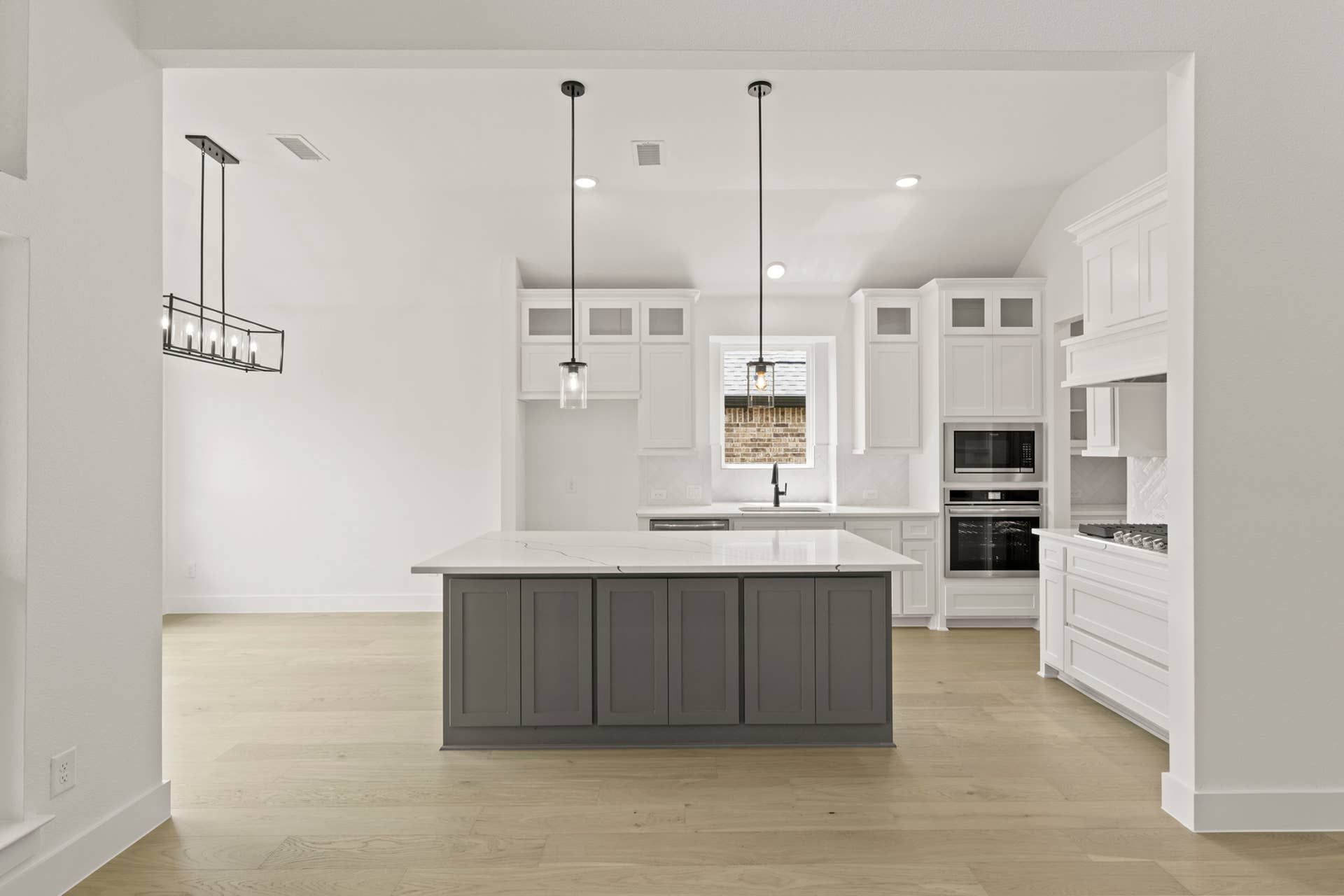 Spacious modern kitchen with white cabinetry and central island in open layout.