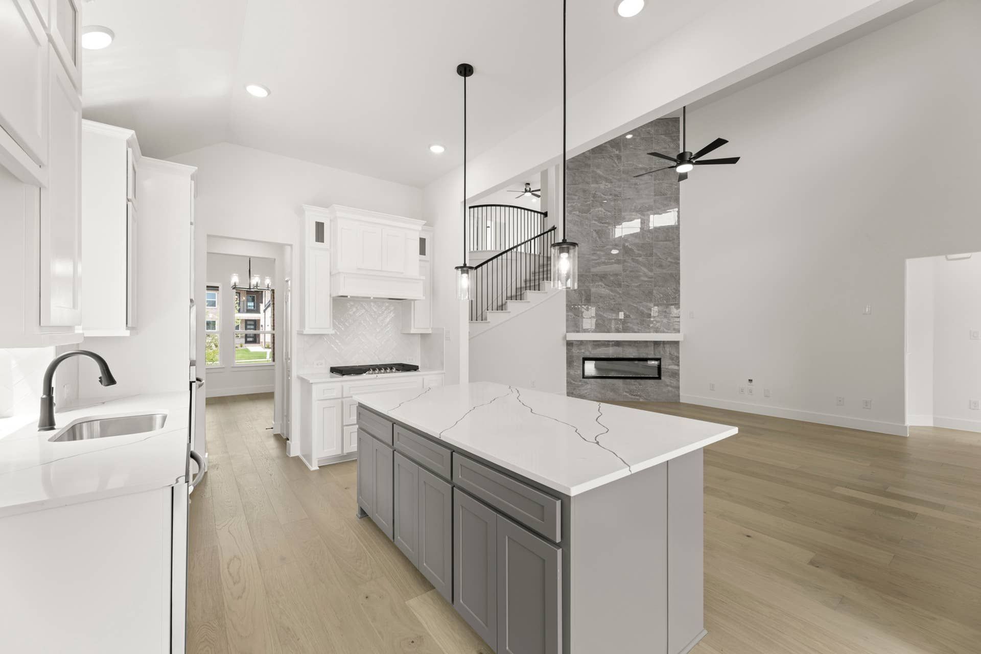 Modern kitchen with marble island, white cabinets, and open living space.
