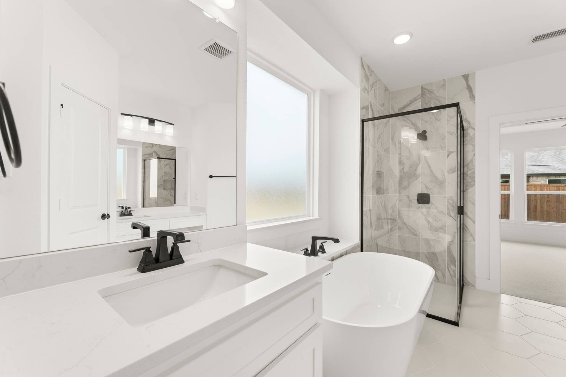 Modern bathroom with freestanding tub, marble shower, and elegant fixtures.