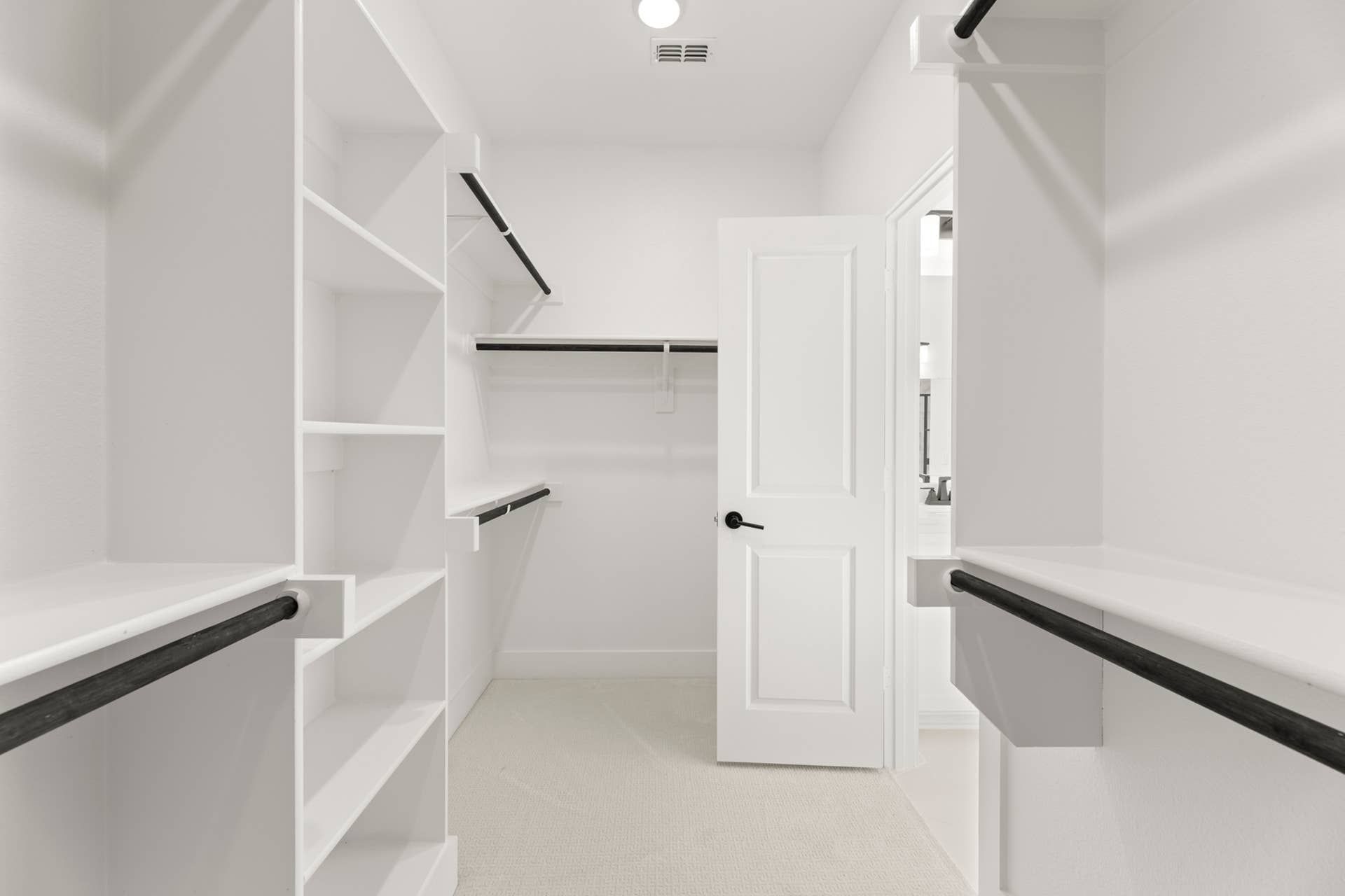 Spacious walk-in closet with white shelving and hanging rods.