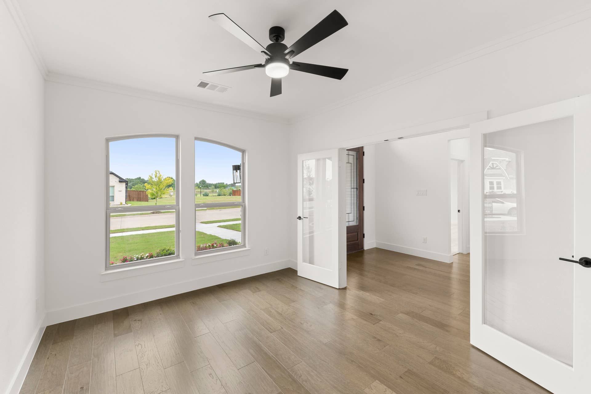 Bright study room with wood flooring and glass French doors.