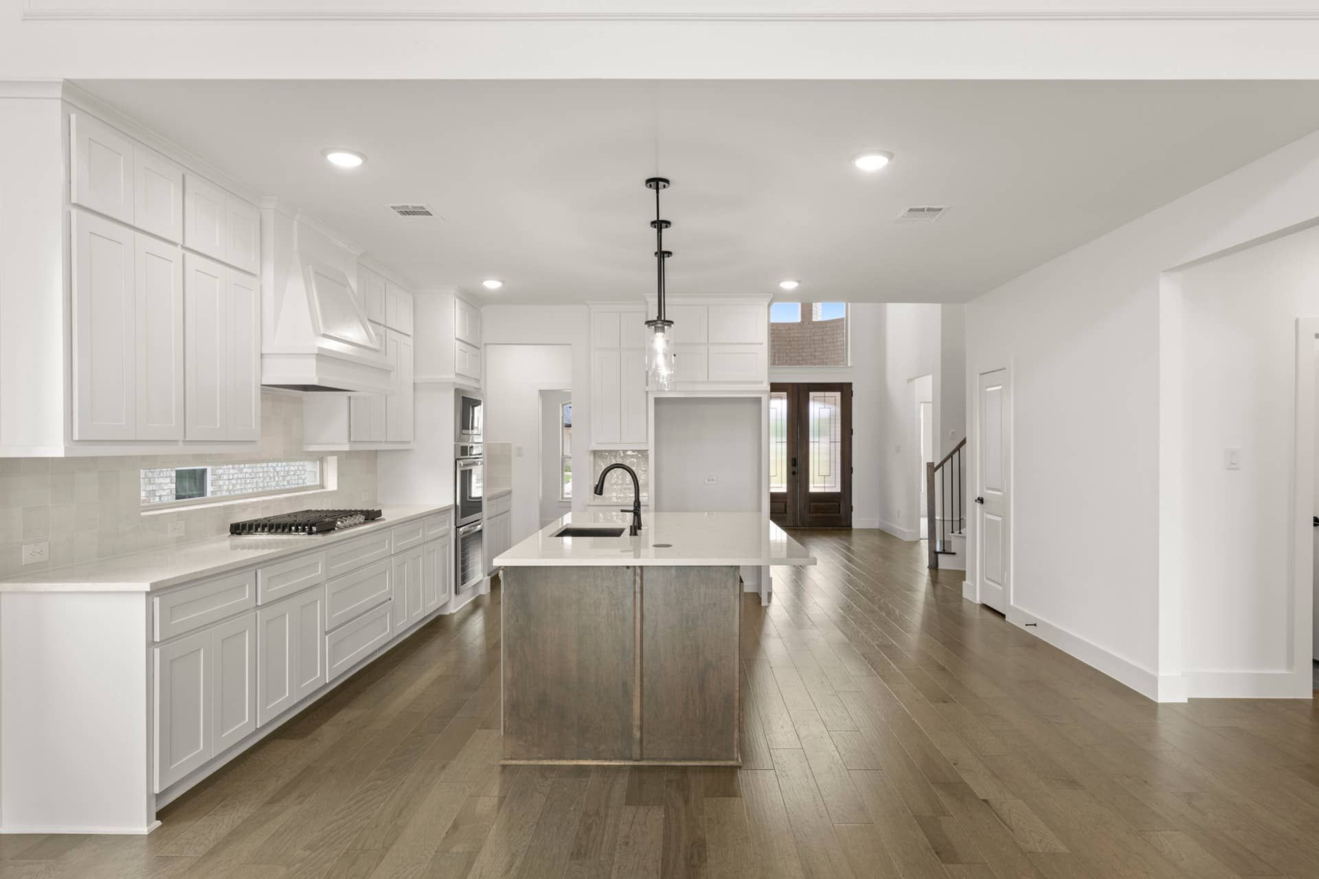 Spacious modern kitchen with white cabinetry and central island.