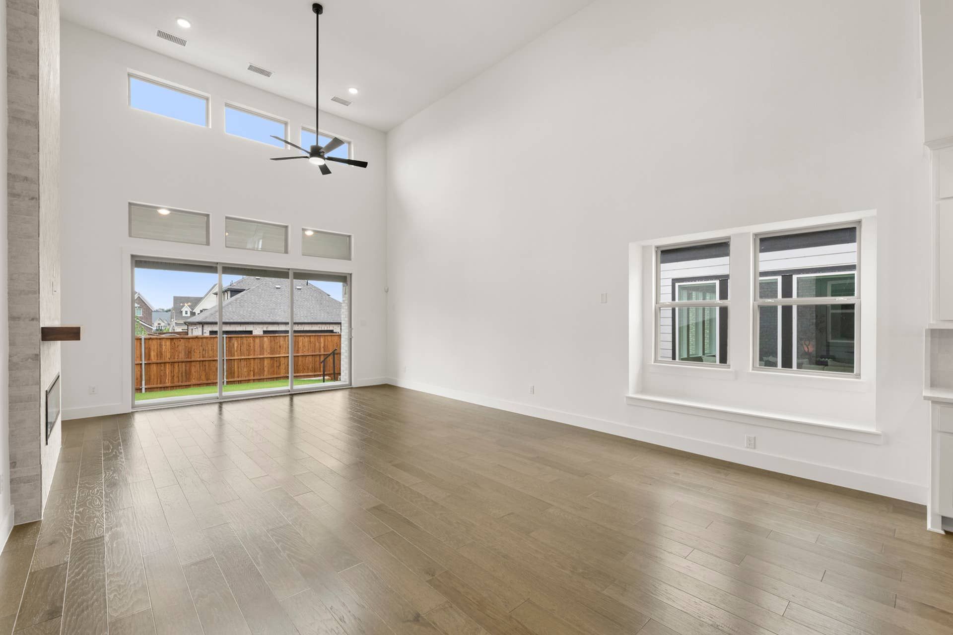Spacious living area with high ceilings, large windows, and hardwood flooring.