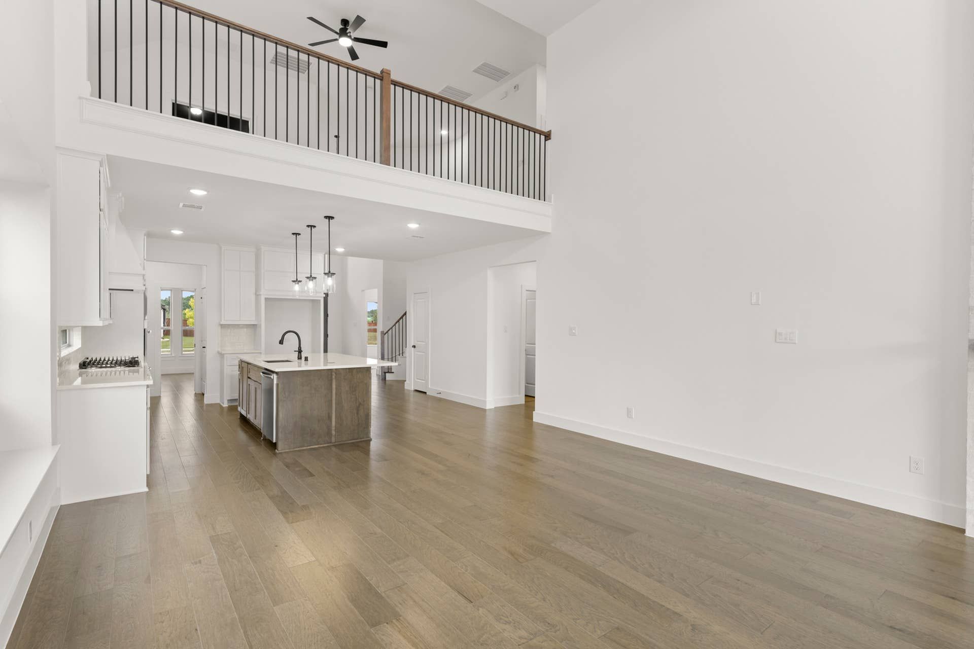 Spacious modern kitchen with island, high ceilings, and open loft area.