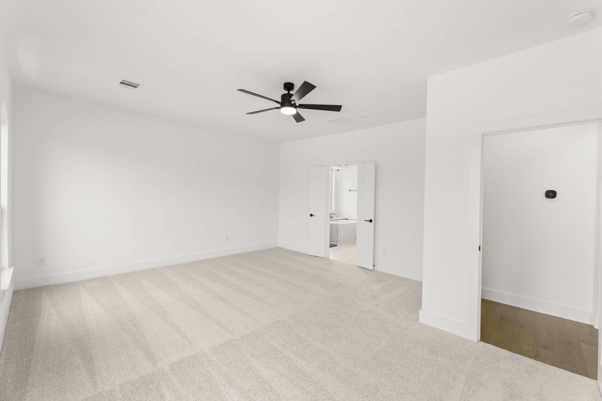 Spacious carpeted bedroom with ceiling fan and en-suite bathroom.