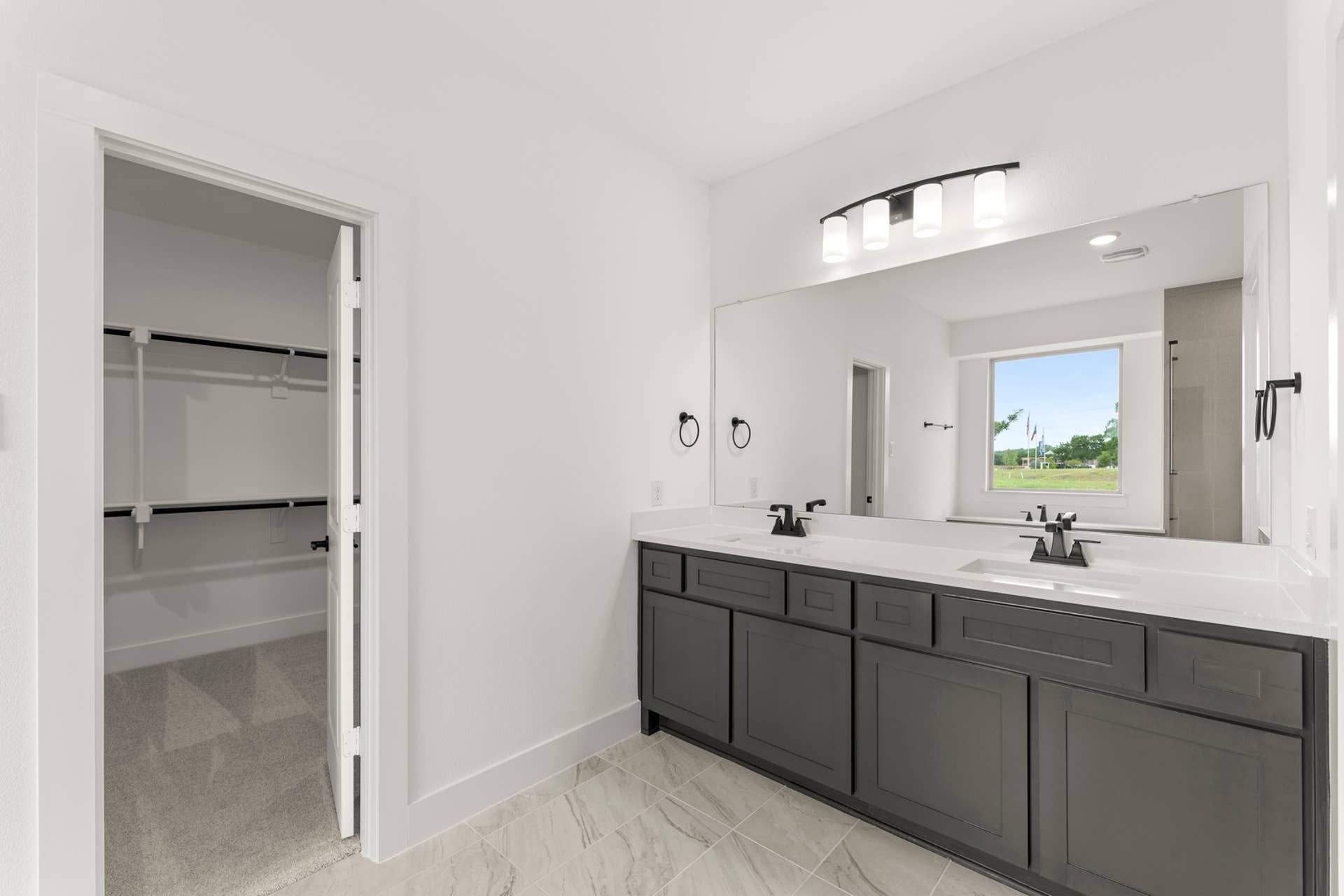 Modern bathroom with dual sinks, large mirror, and walk-in closet.