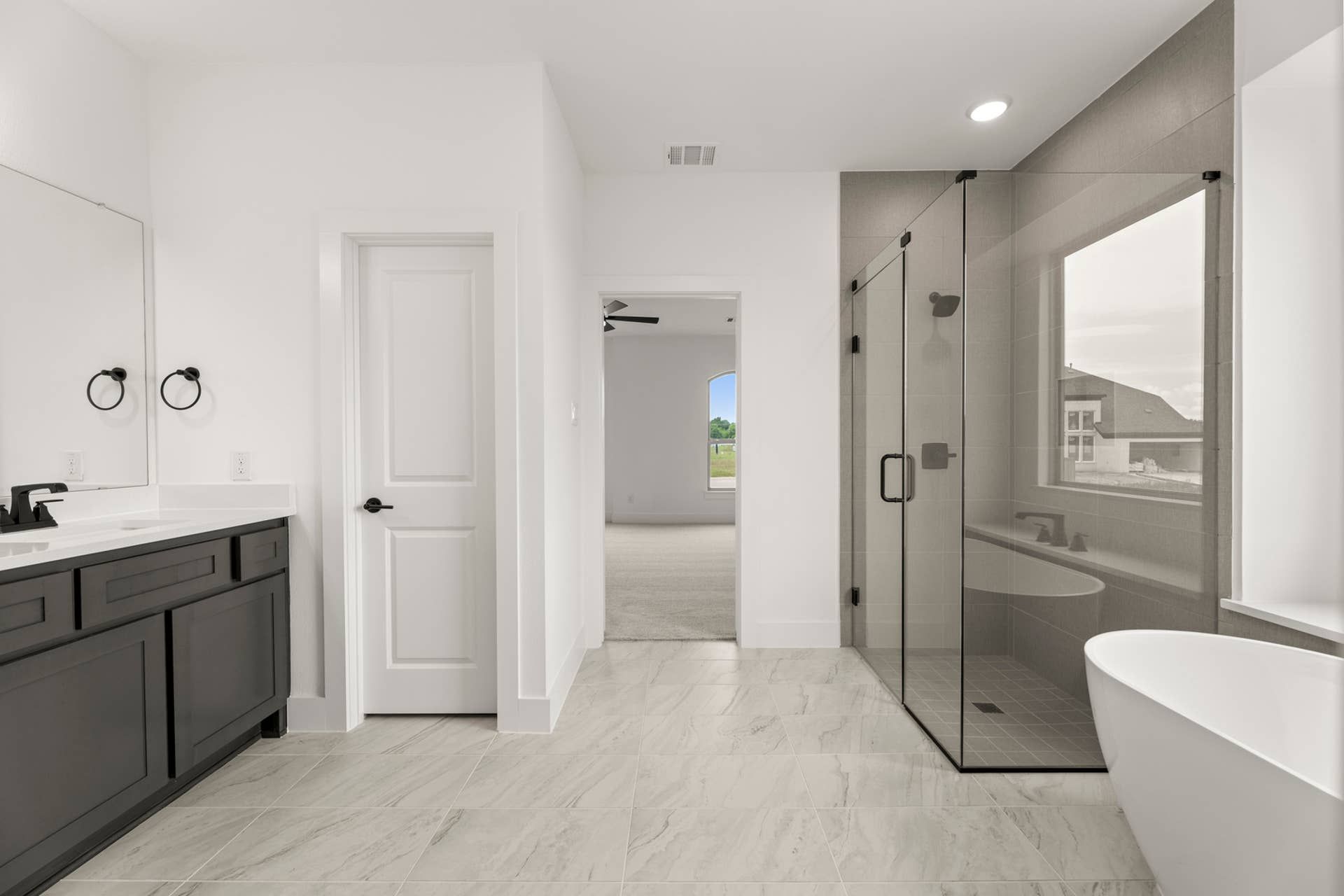 Modern bathroom with glass shower, freestanding tub, and dual-sink vanity.