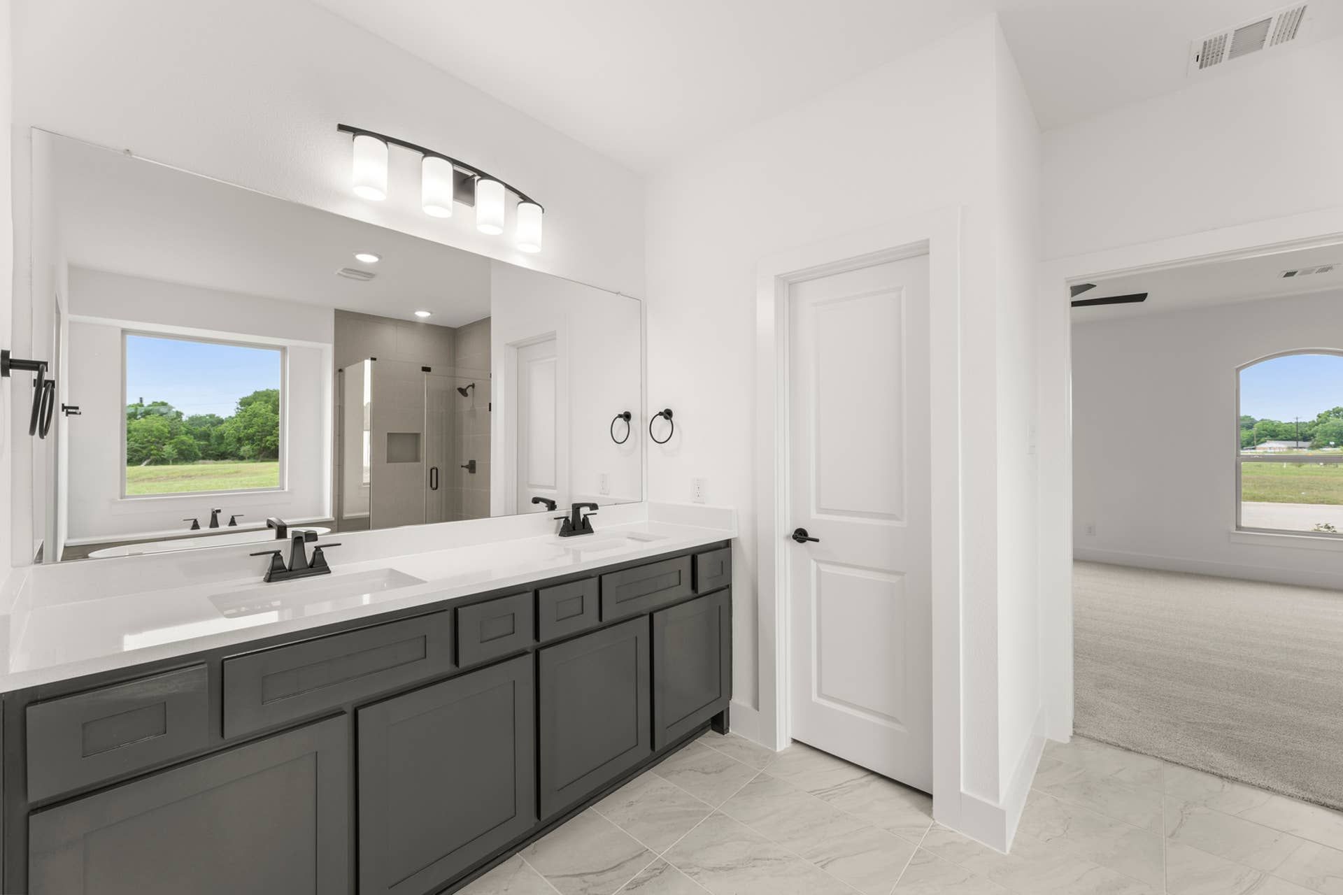 Modern bathroom with dual sinks, large mirror, and natural light.