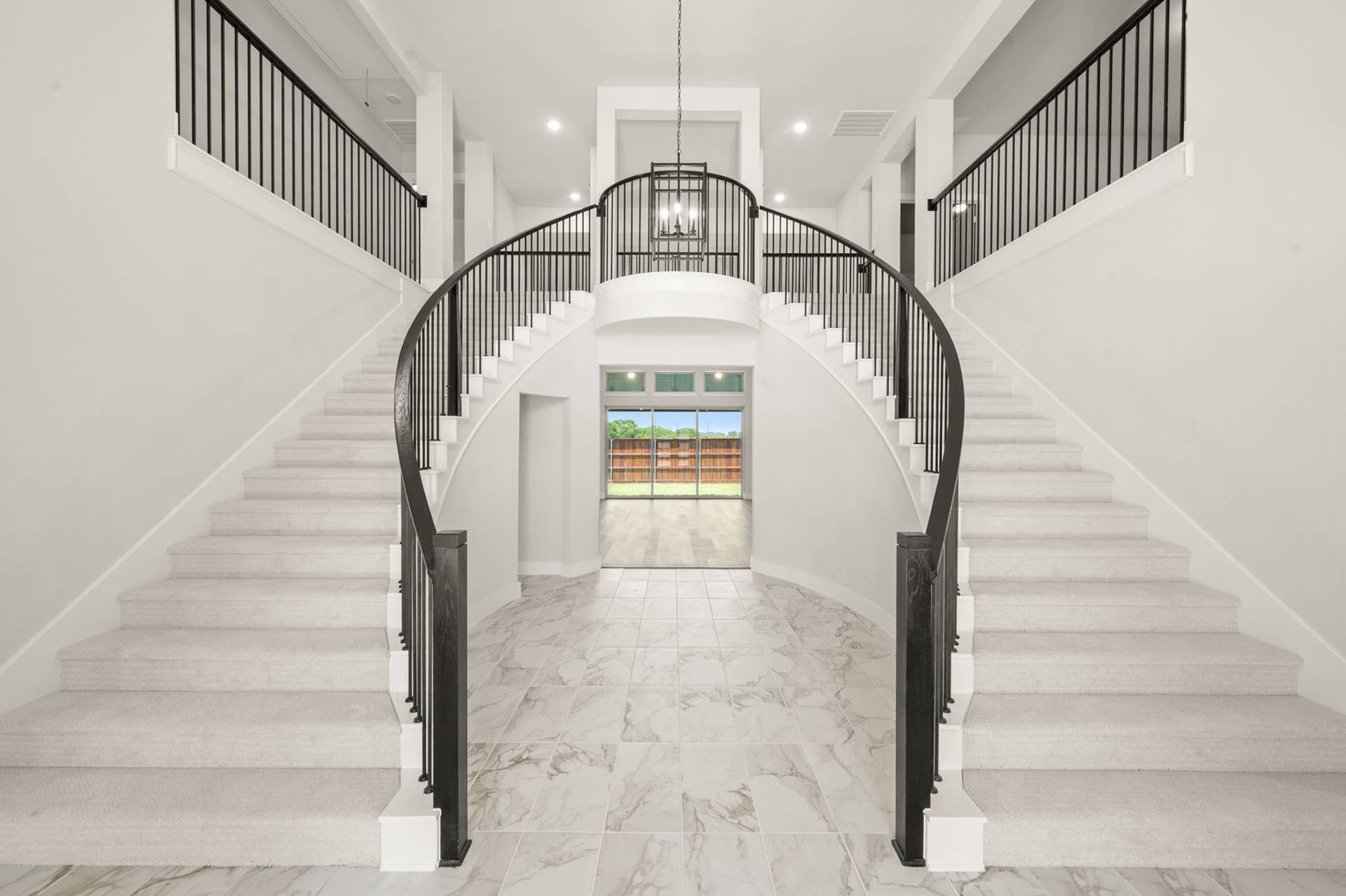 Grand entryway with elegant dual staircase and marble flooring.